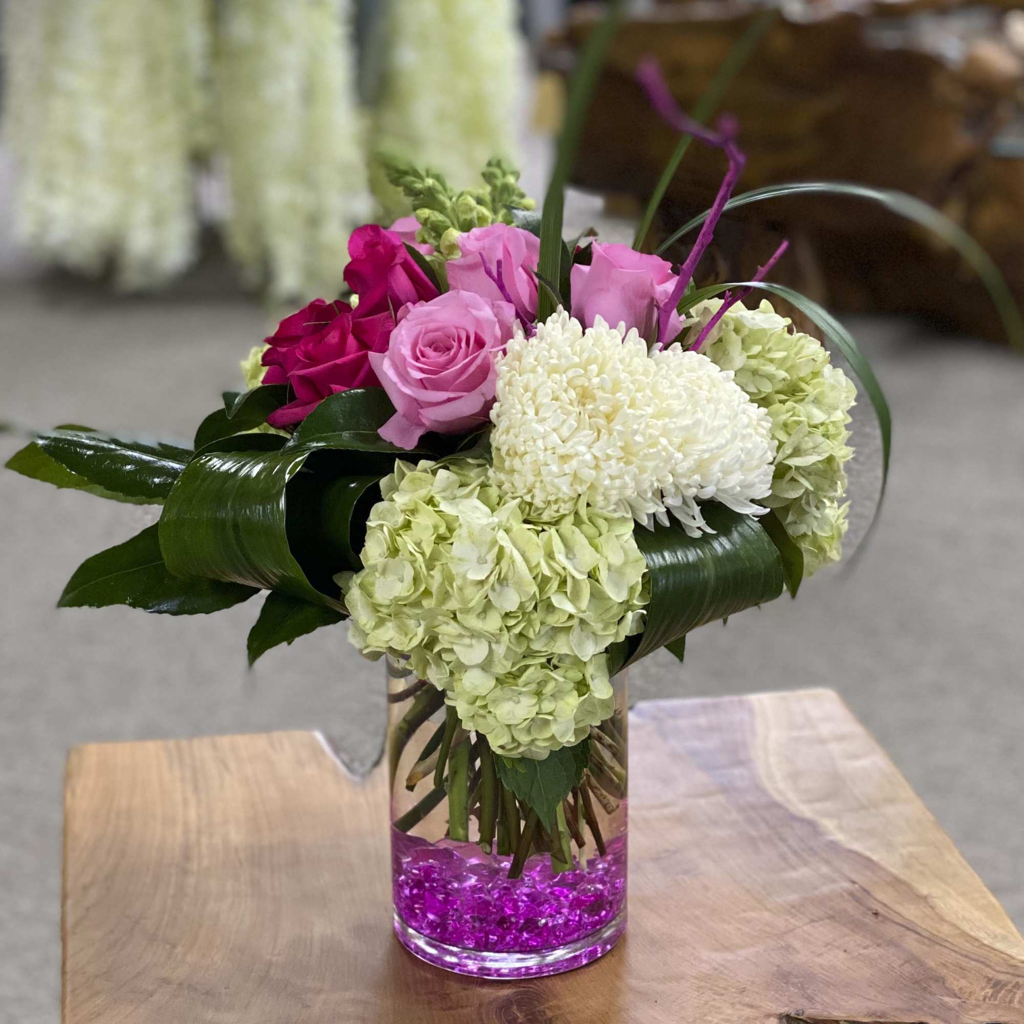 Pink roses and white hydrangeas in a clear glass vase with pink stones