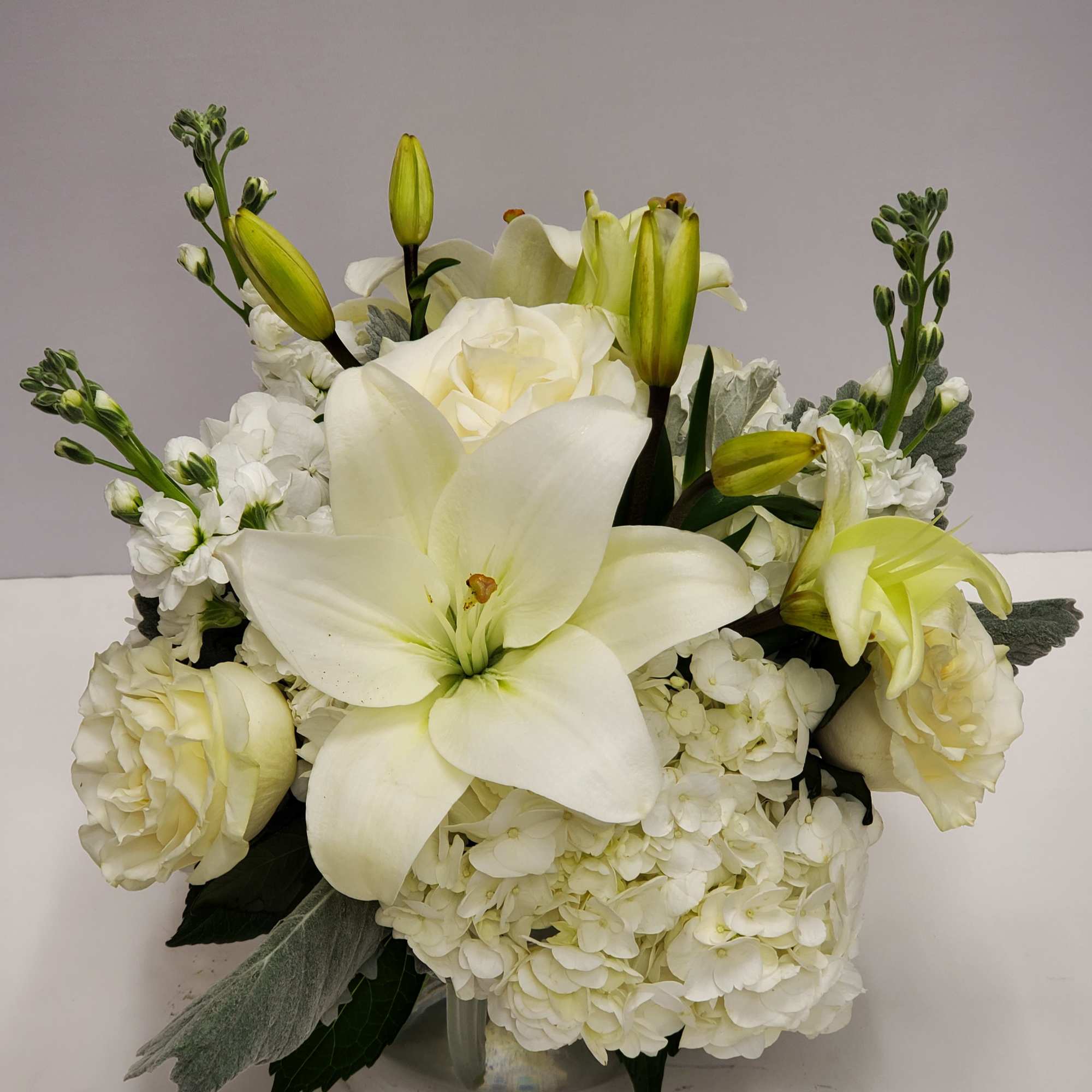 This arrangement includes white roses, white asiatic lilies, white stock, and dusty, photo 2 of 2