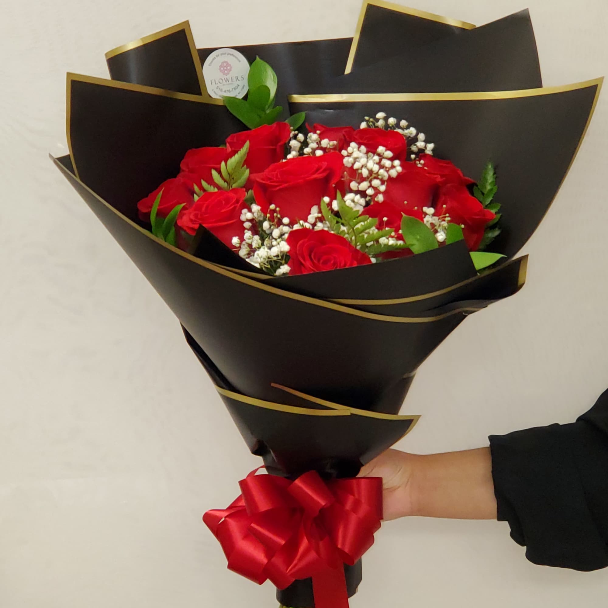 Bouquet of red roses wrapped in black paper with a red ribbon