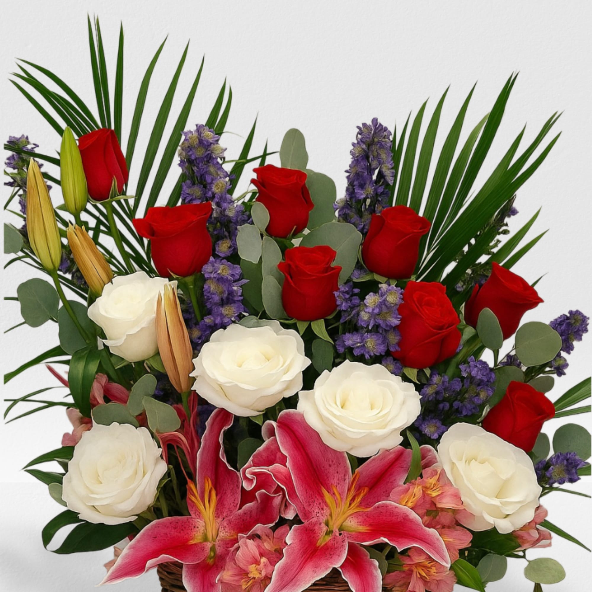 Basket arrangement of red and white roses with pink lilies and purple flowers.