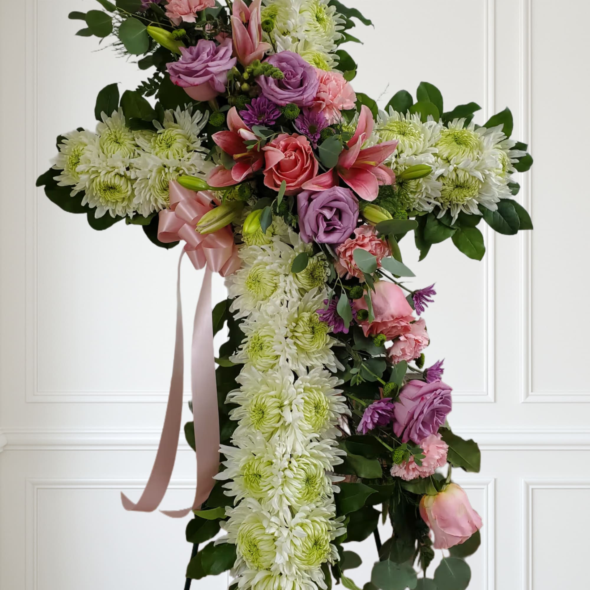 White cross with soft color flowers pinks and purples.