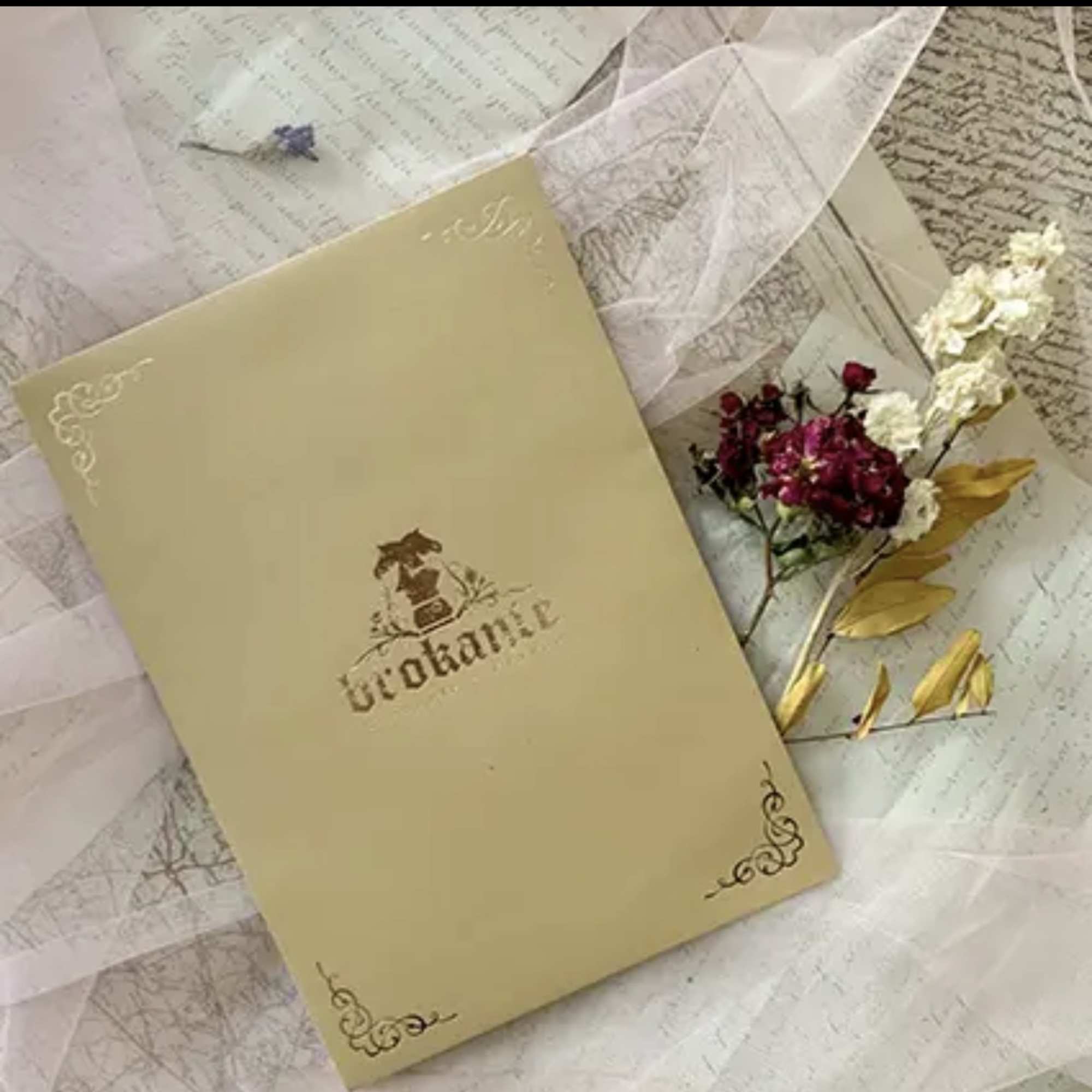 Gift box with small pink and white flowers and gold leaves on patterned paper