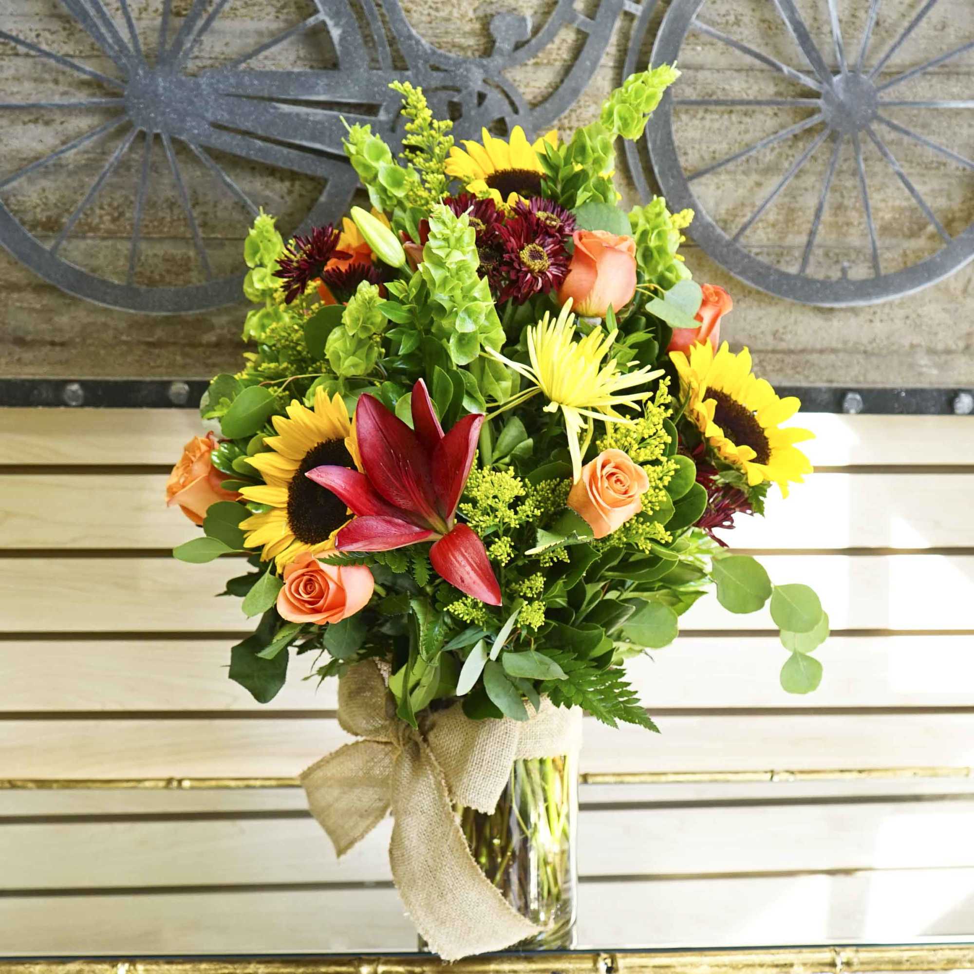 Mixed bouquet with sunflowers, roses, and lilies in a glass vase