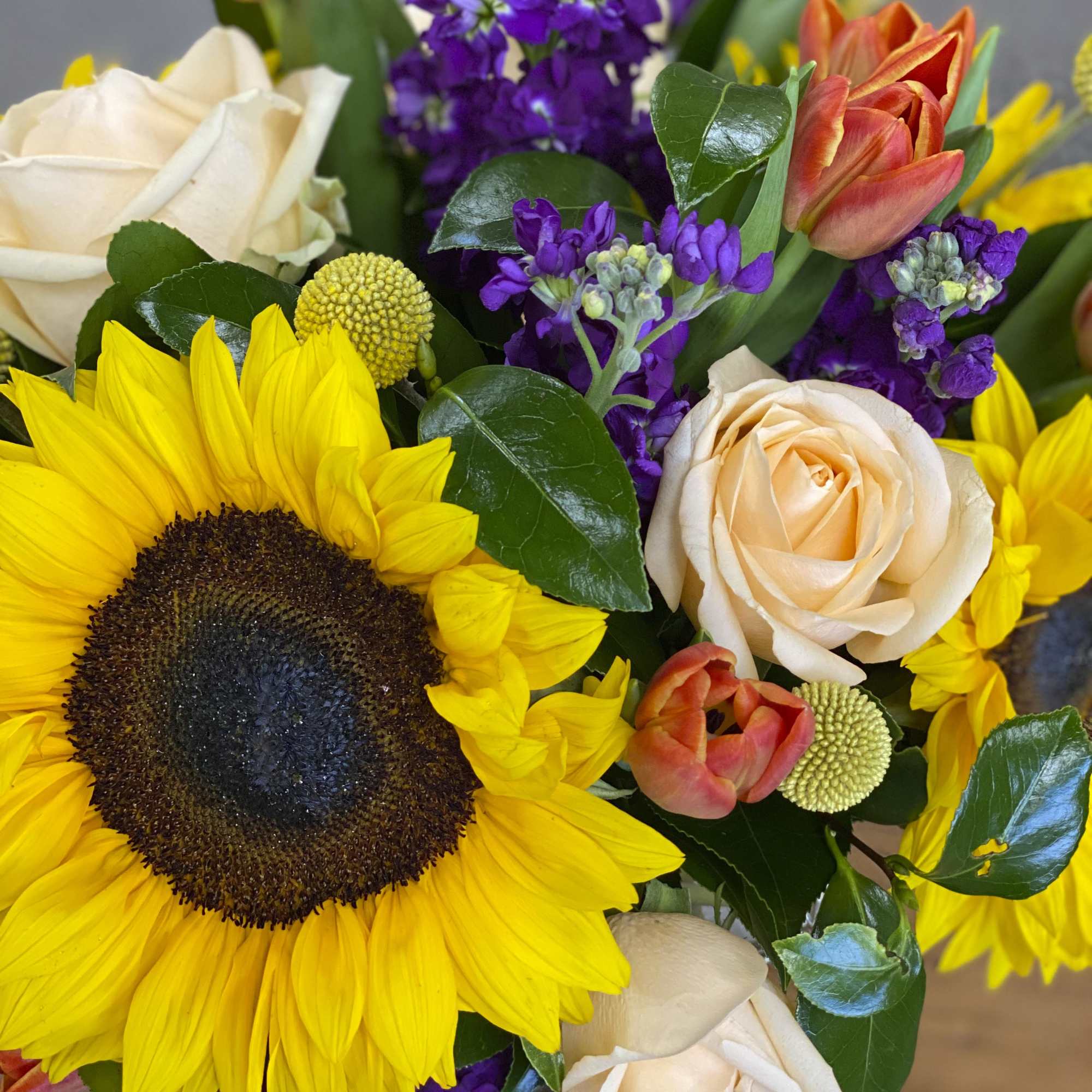 Bouquet of sunflowers, cream roses, and purple flowers