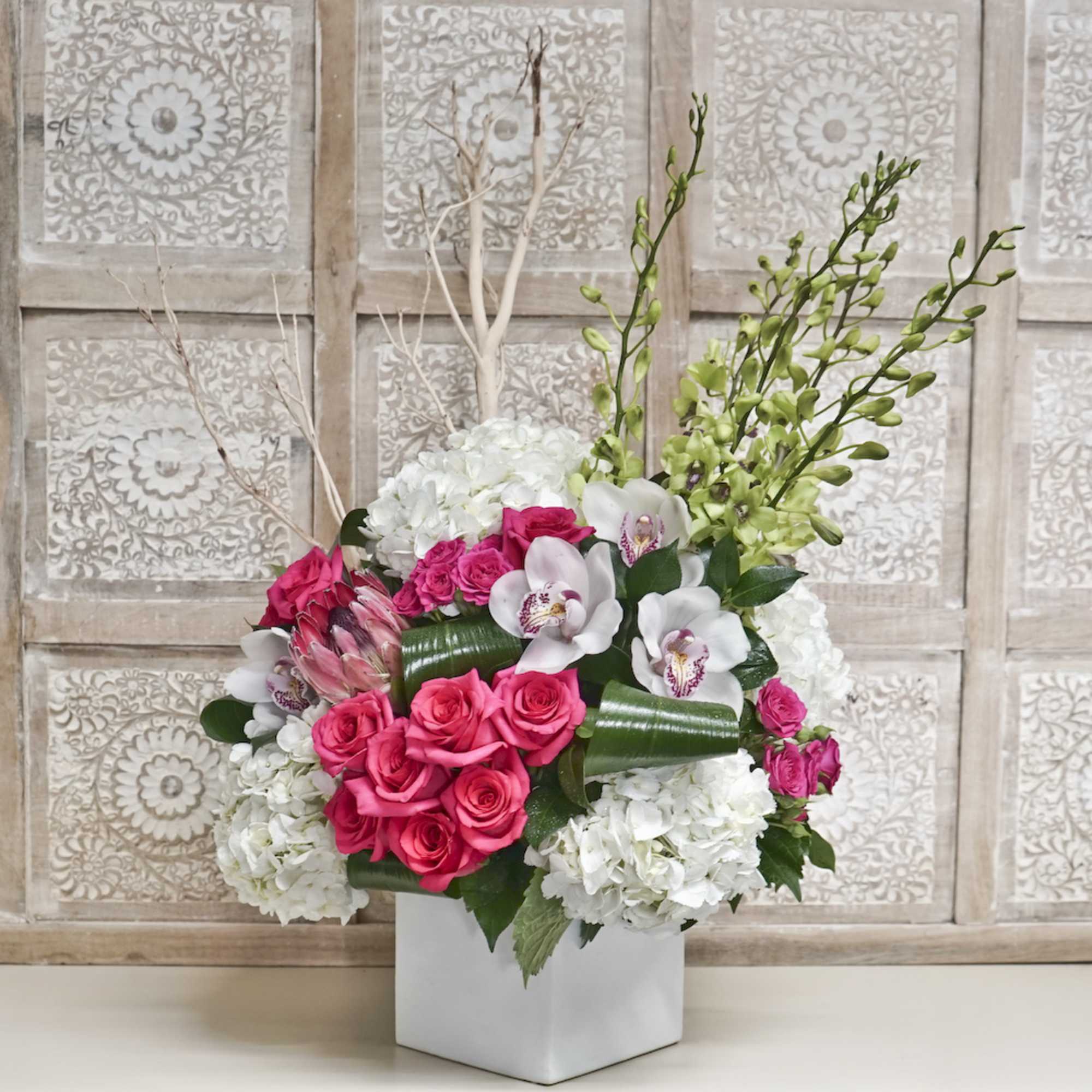 Pink roses and white orchids arranged in a white vase
