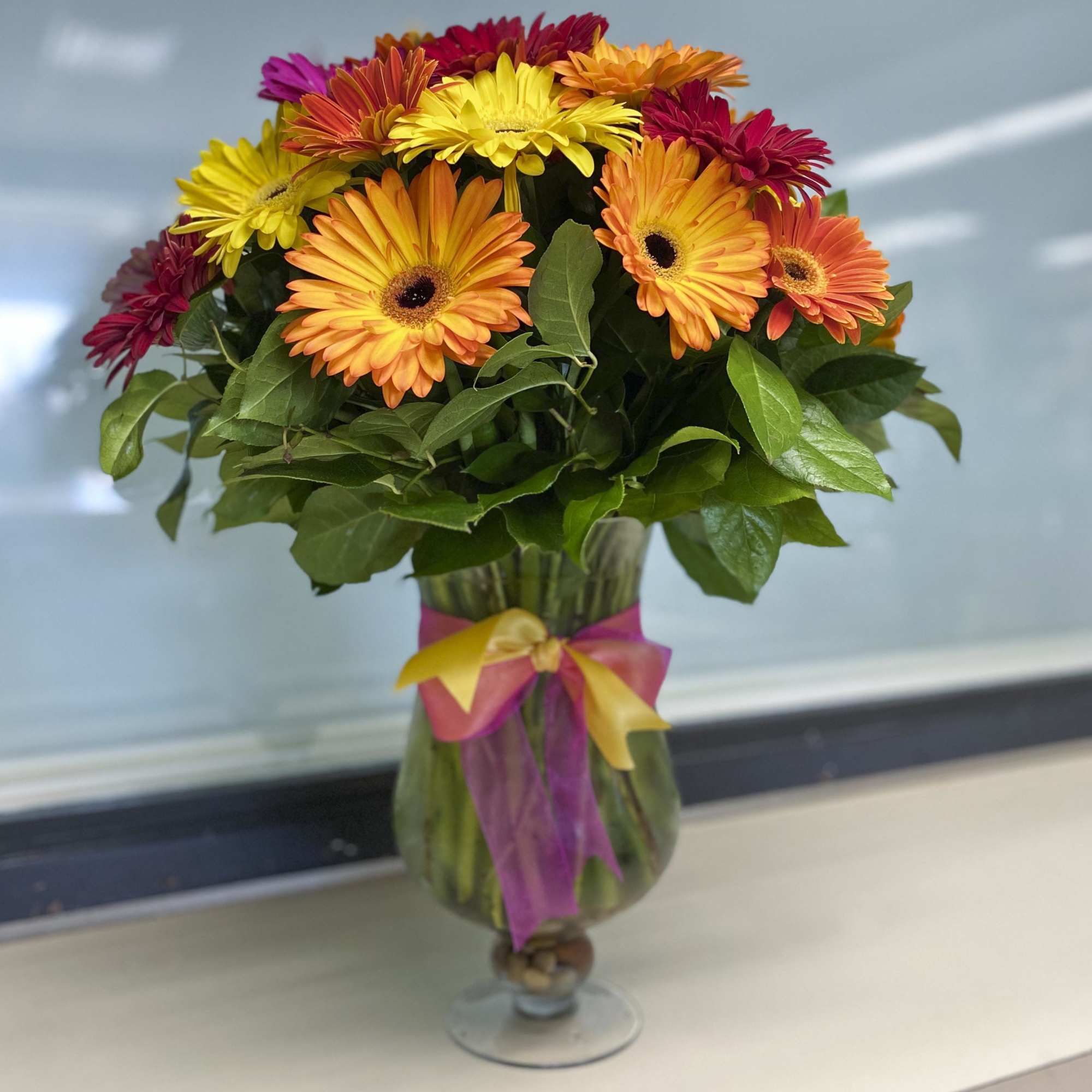 Colorful gerbera daisy bouquet in a glass vase with ribbon
