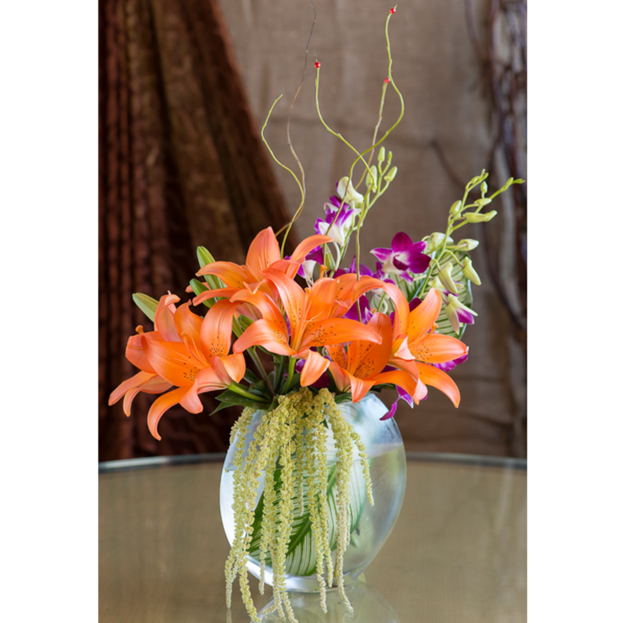 Orange lilies and purple orchids in a clear glass vase, photo 4 of 5
