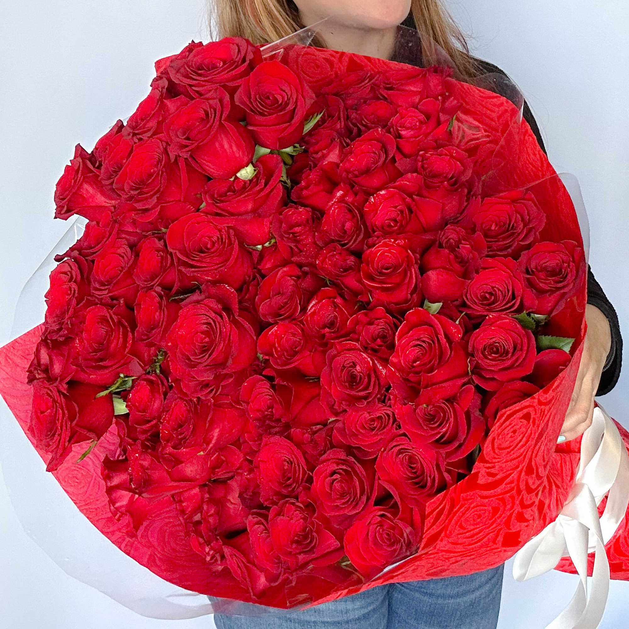 Large bouquet of red roses wrapped in red paper with a white ribbon
