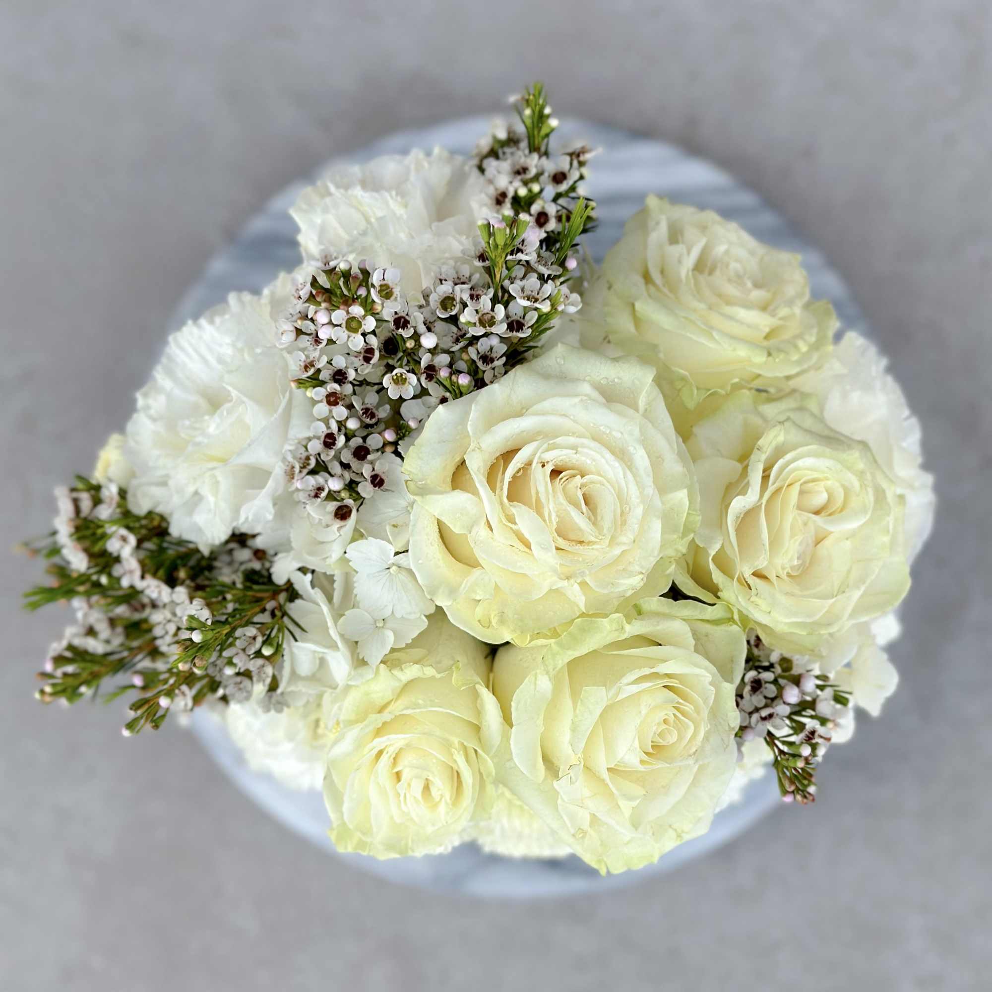 Cream roses with white filler flowers in a round bouquet