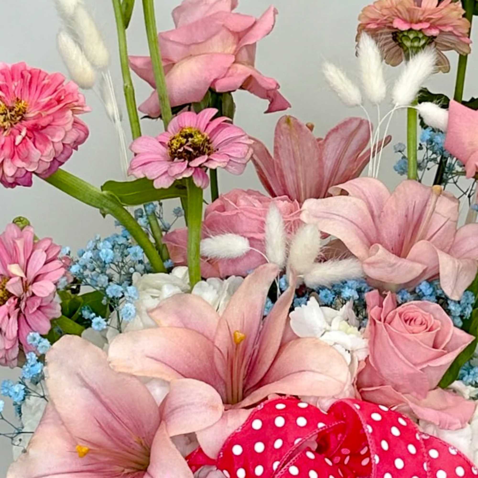 Pink flowers with blue filler and a red polka-dot ribbon