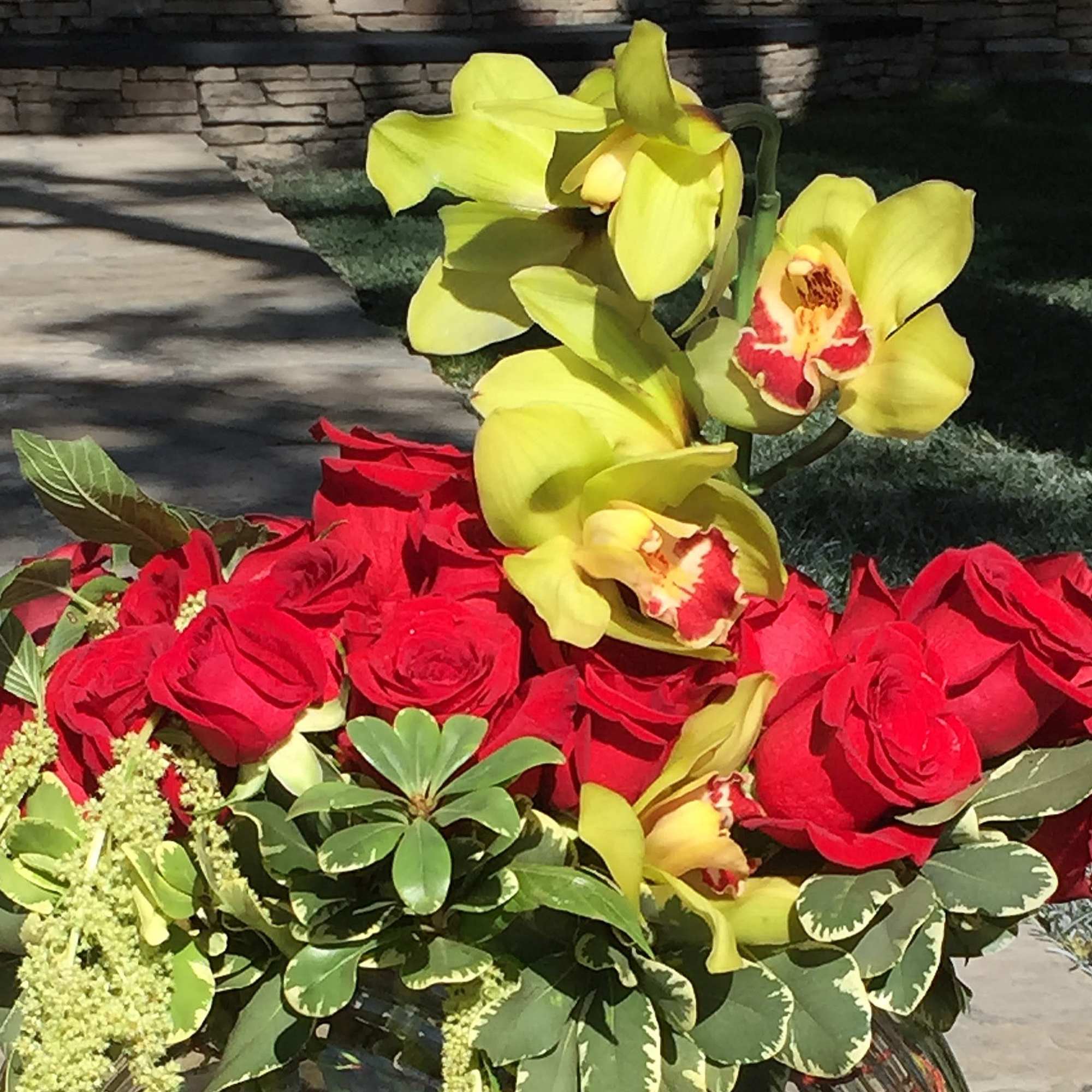 Bouquet of red roses and yellow orchids with mixed greenery