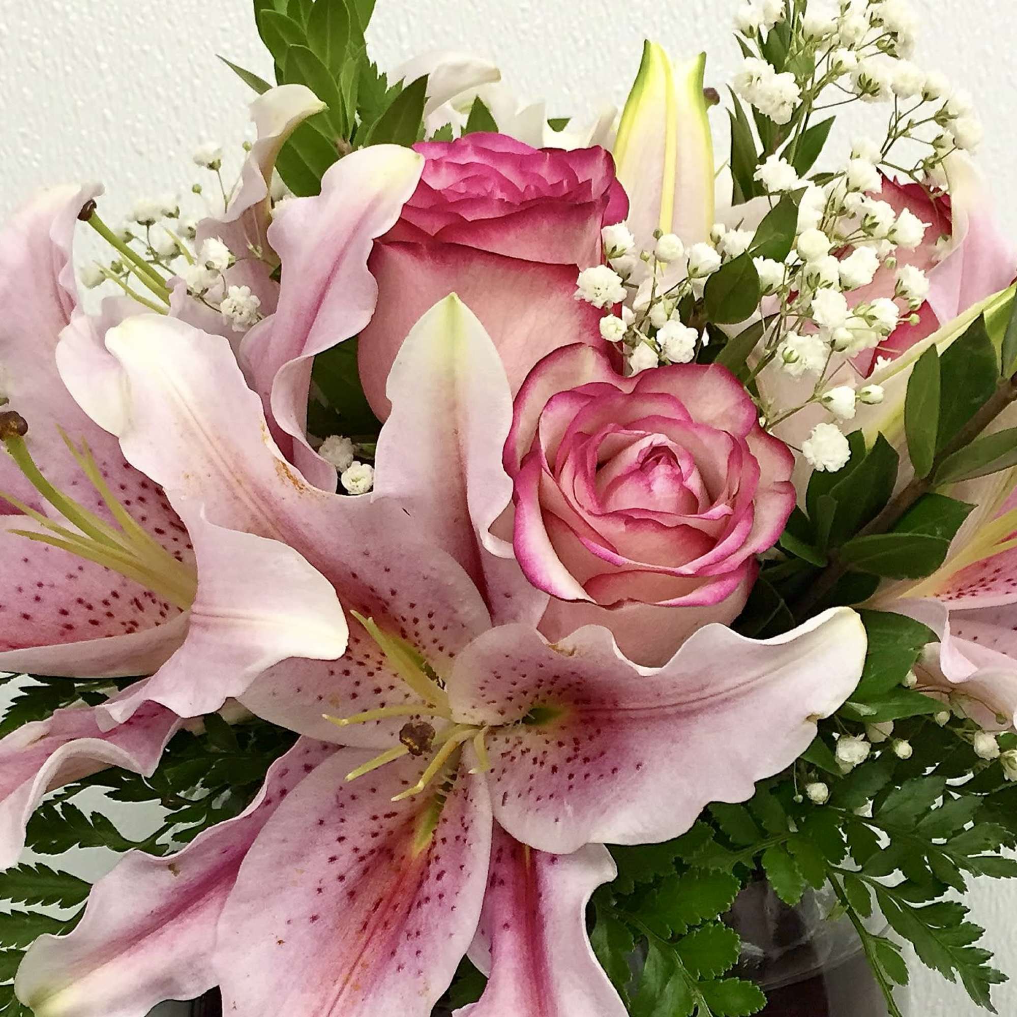 Pink lilies and roses arranged in a vase