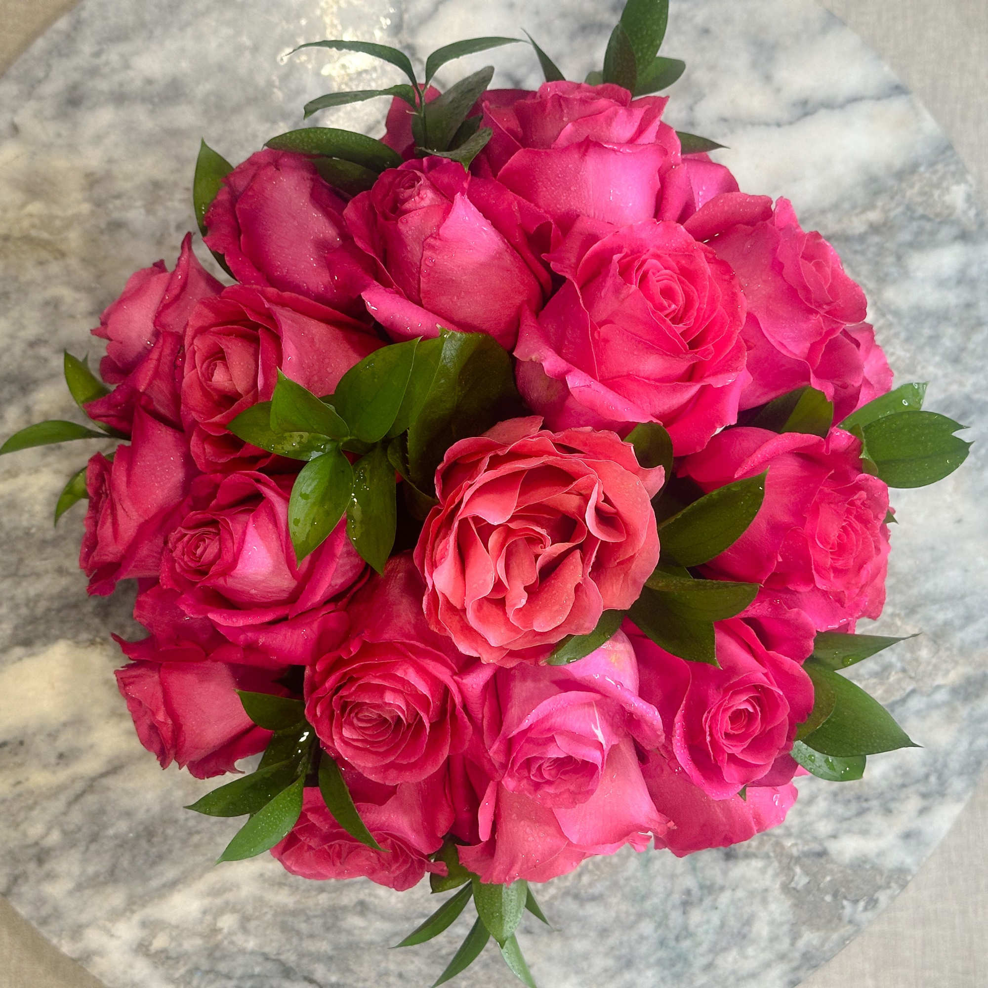 Round bouquet of bright pink roses with green foliage