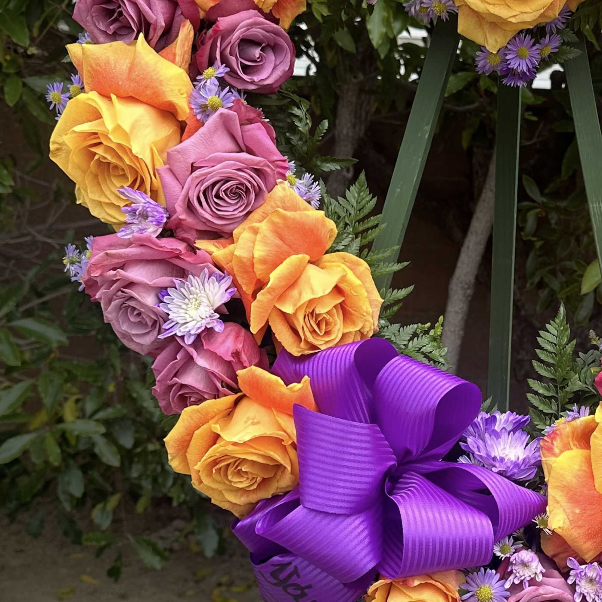 Heart-shaped bouquet of orange and purple roses with a purple ribbon
