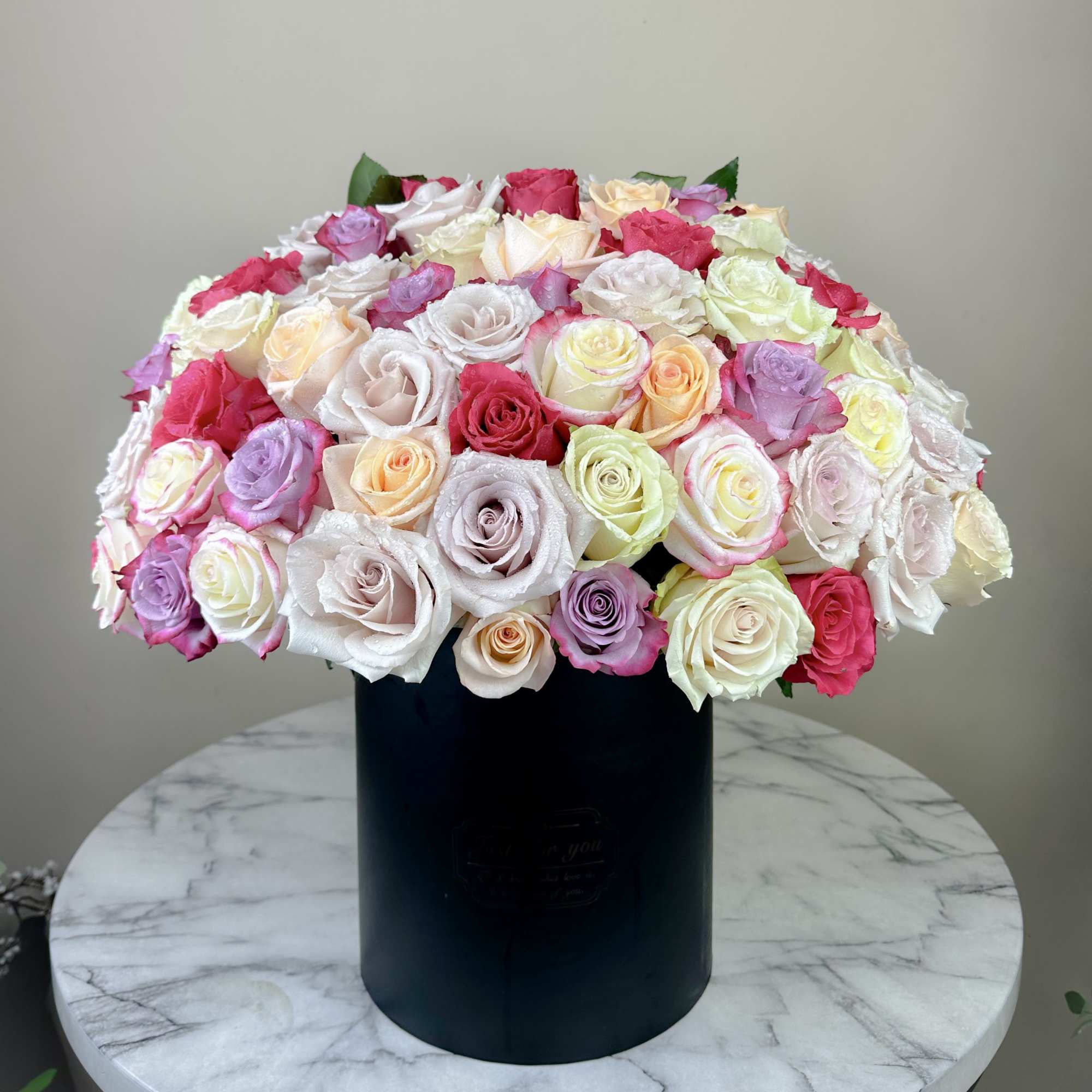 Round bouquet of multicolored roses in a black box