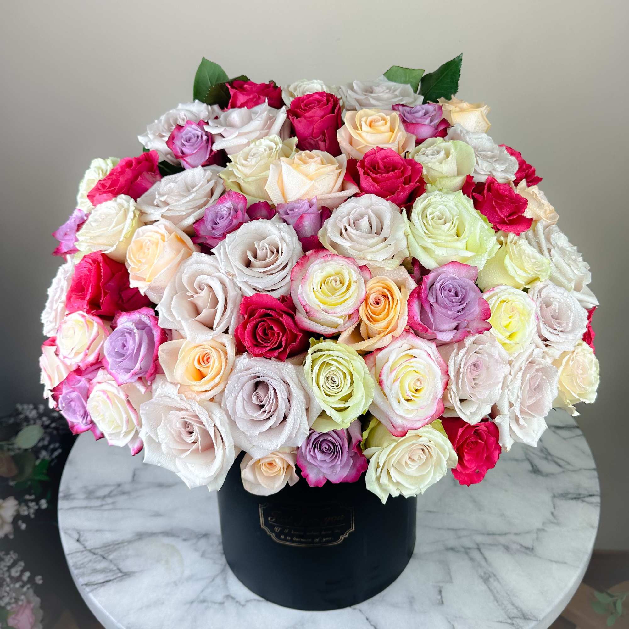 Large bouquet of multicolored roses in a black hat box