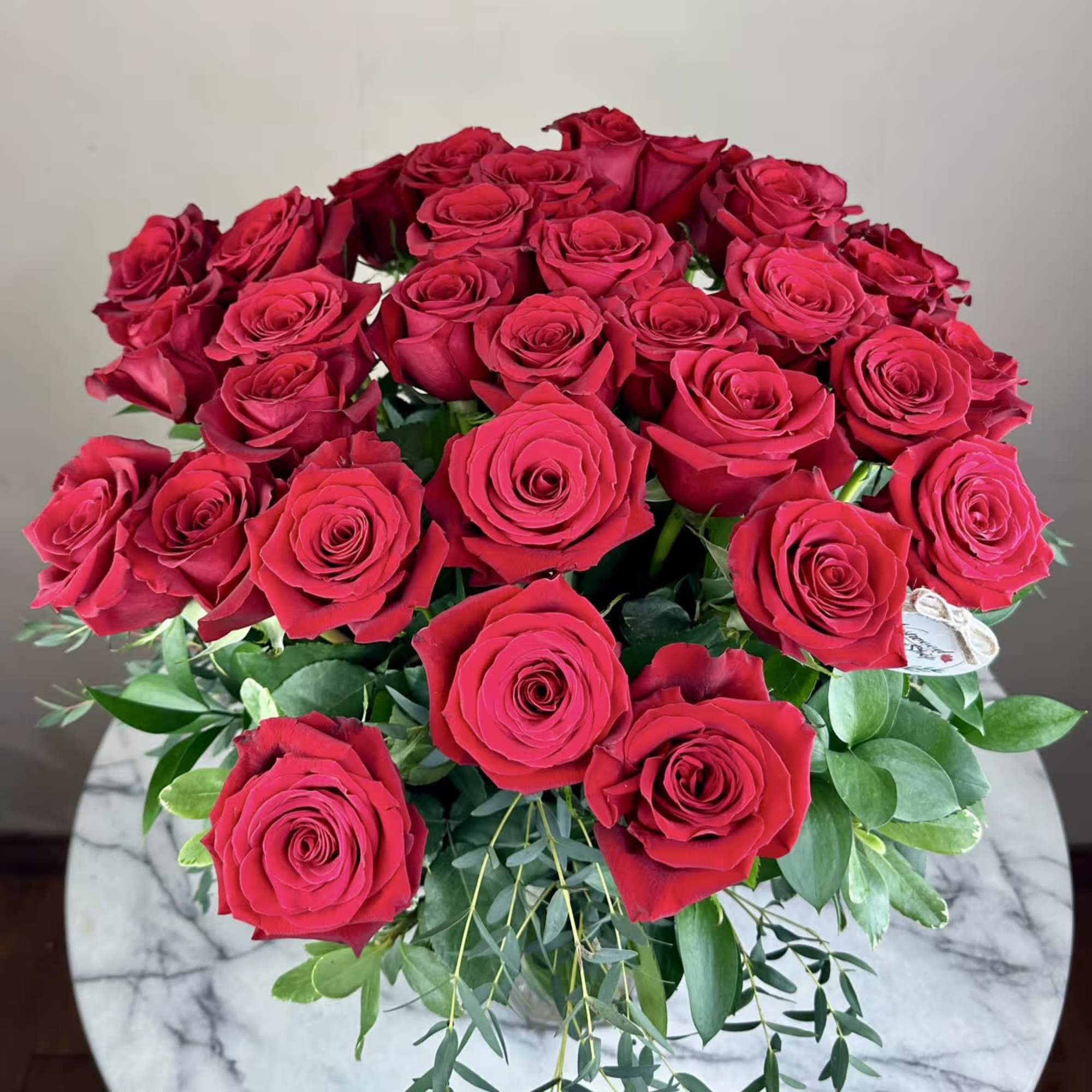 Bouquet of red roses with greenery in a clear vase