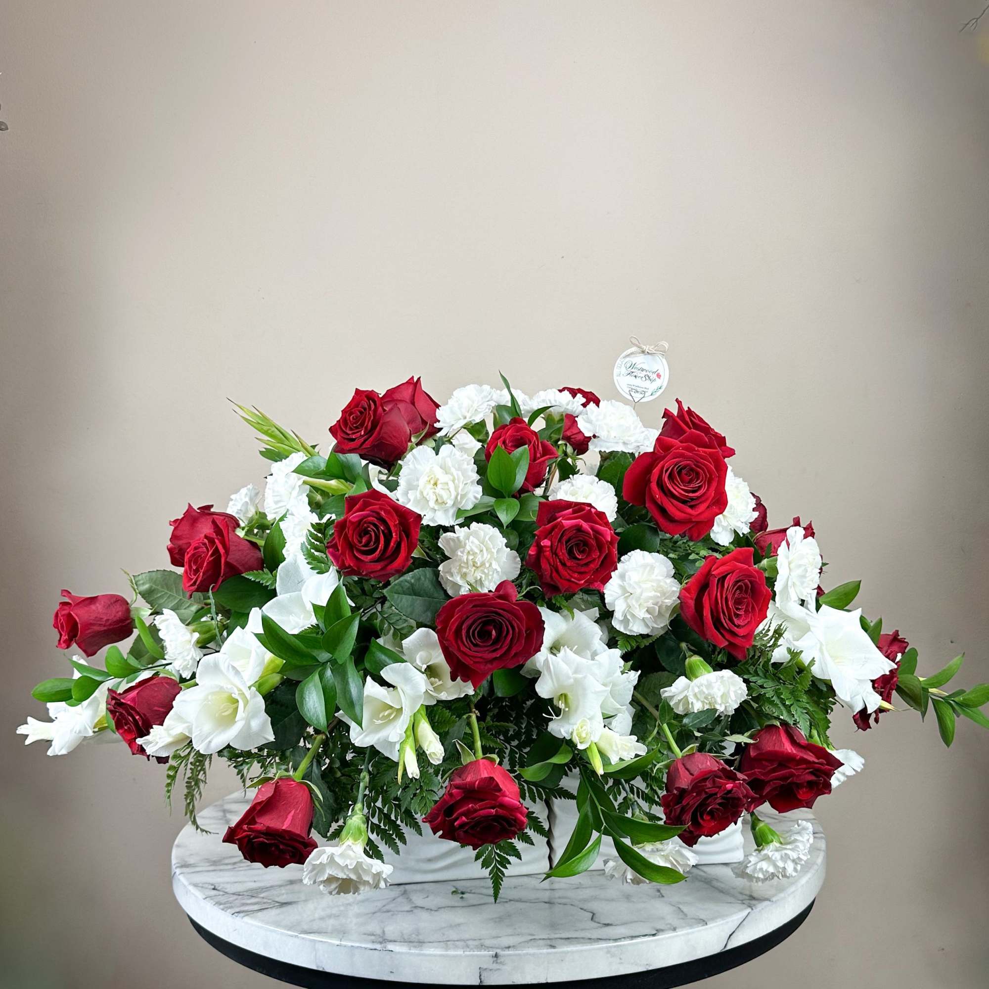 Red roses and white carnations arranged in a low white container