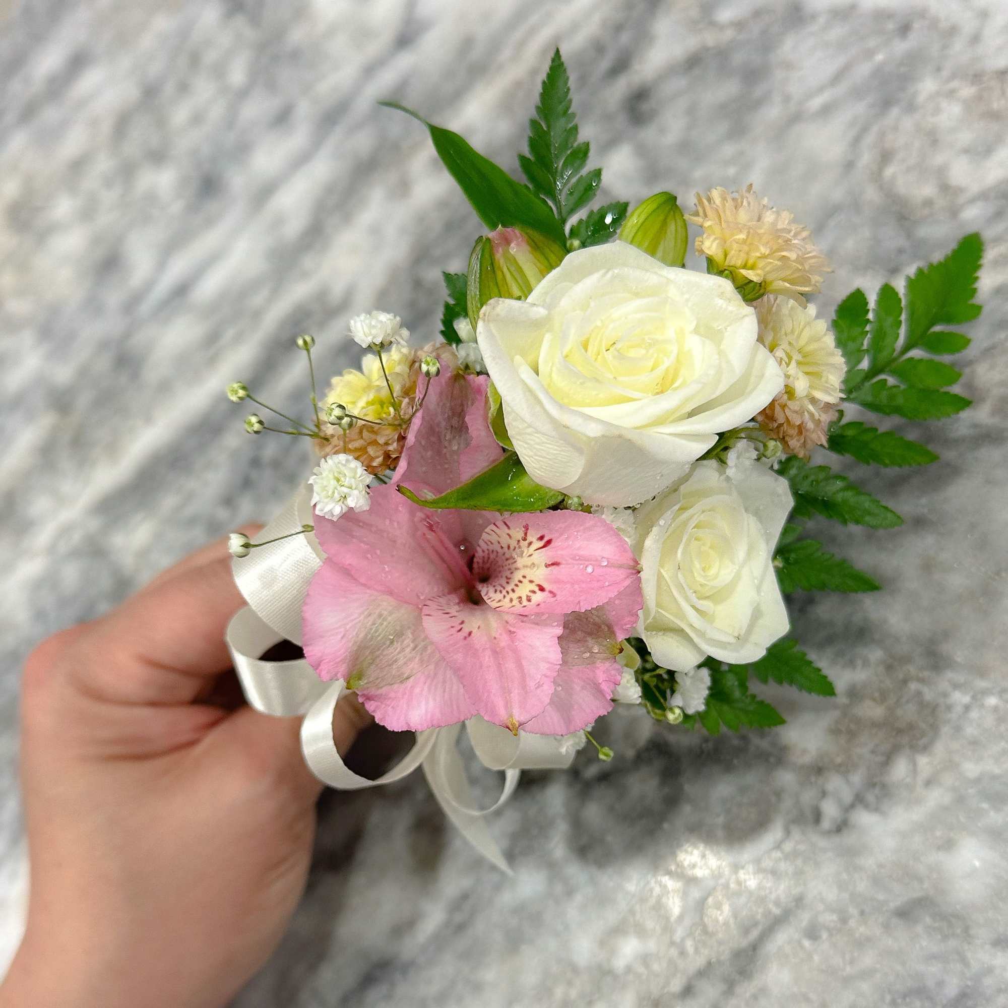 Small bouquet with white roses and a pink lily, tied with white ribbon