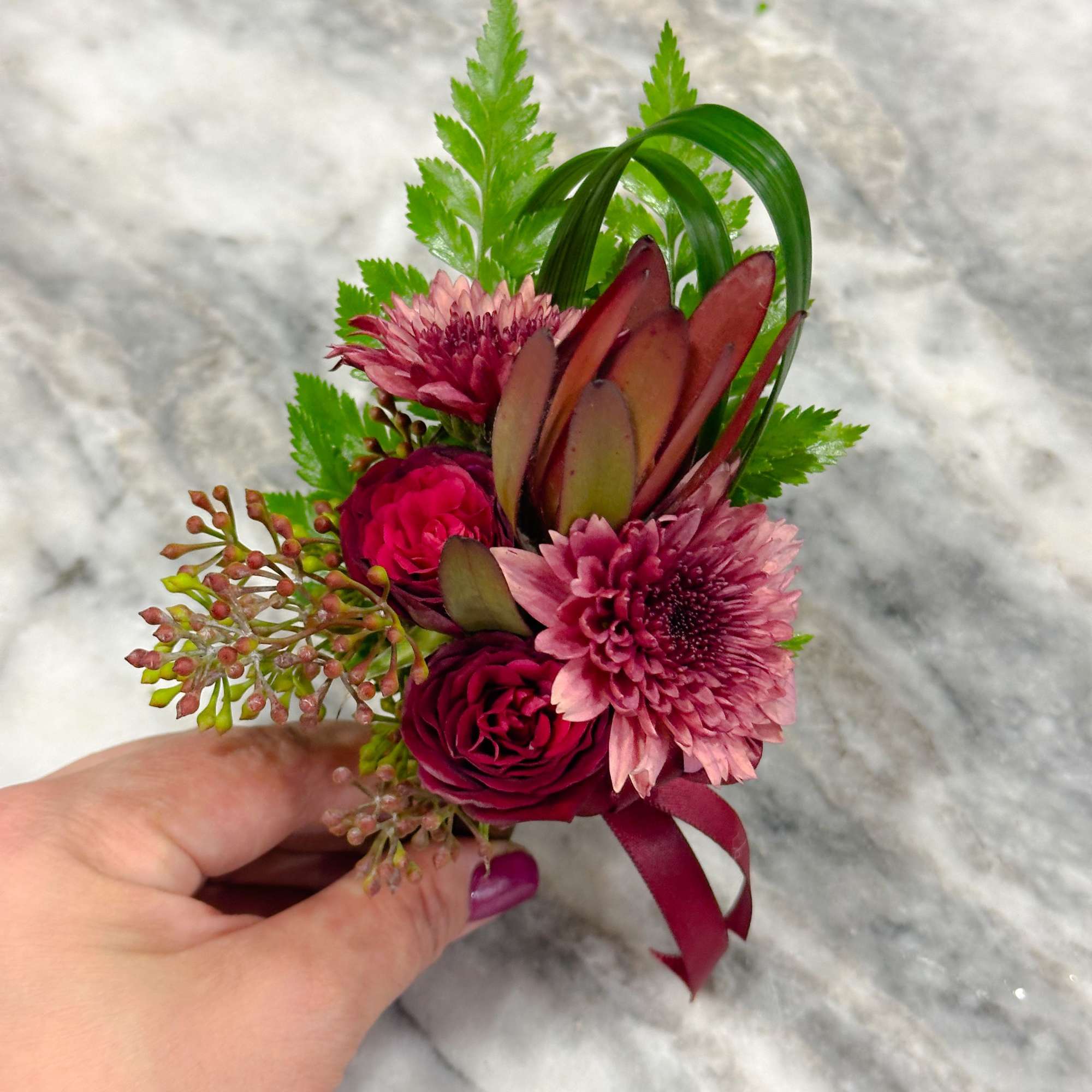 Small burgundy and pink floral corsage with ribbon