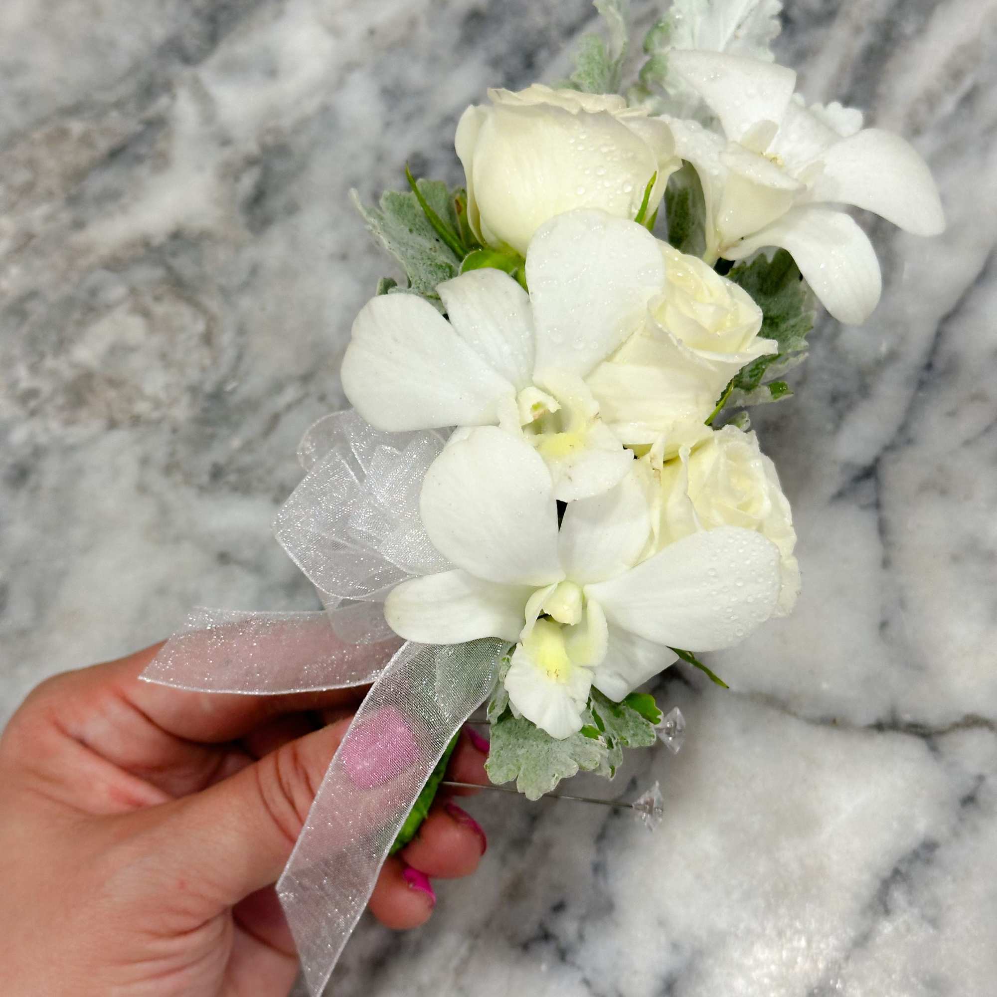 Small white floral corsage with ribbon