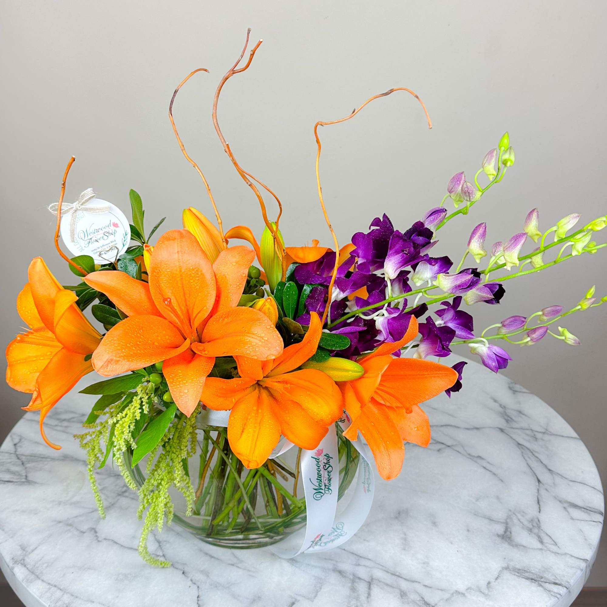 Orange lilies and purple orchids in a glass vase