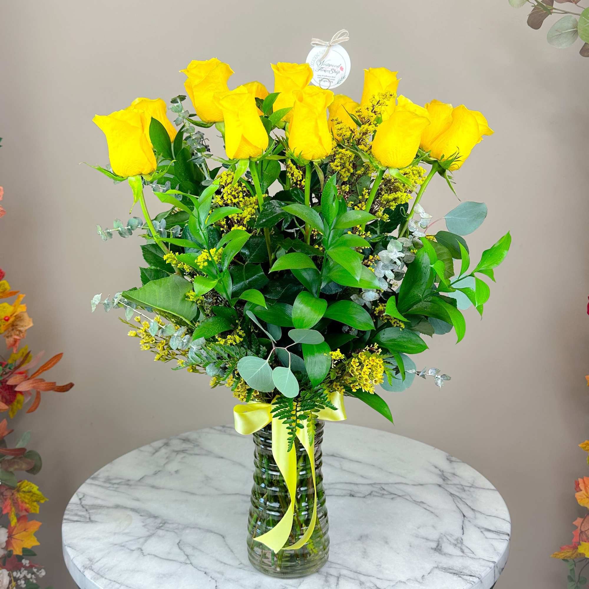 Yellow roses in a clear glass vase with a yellow ribbon