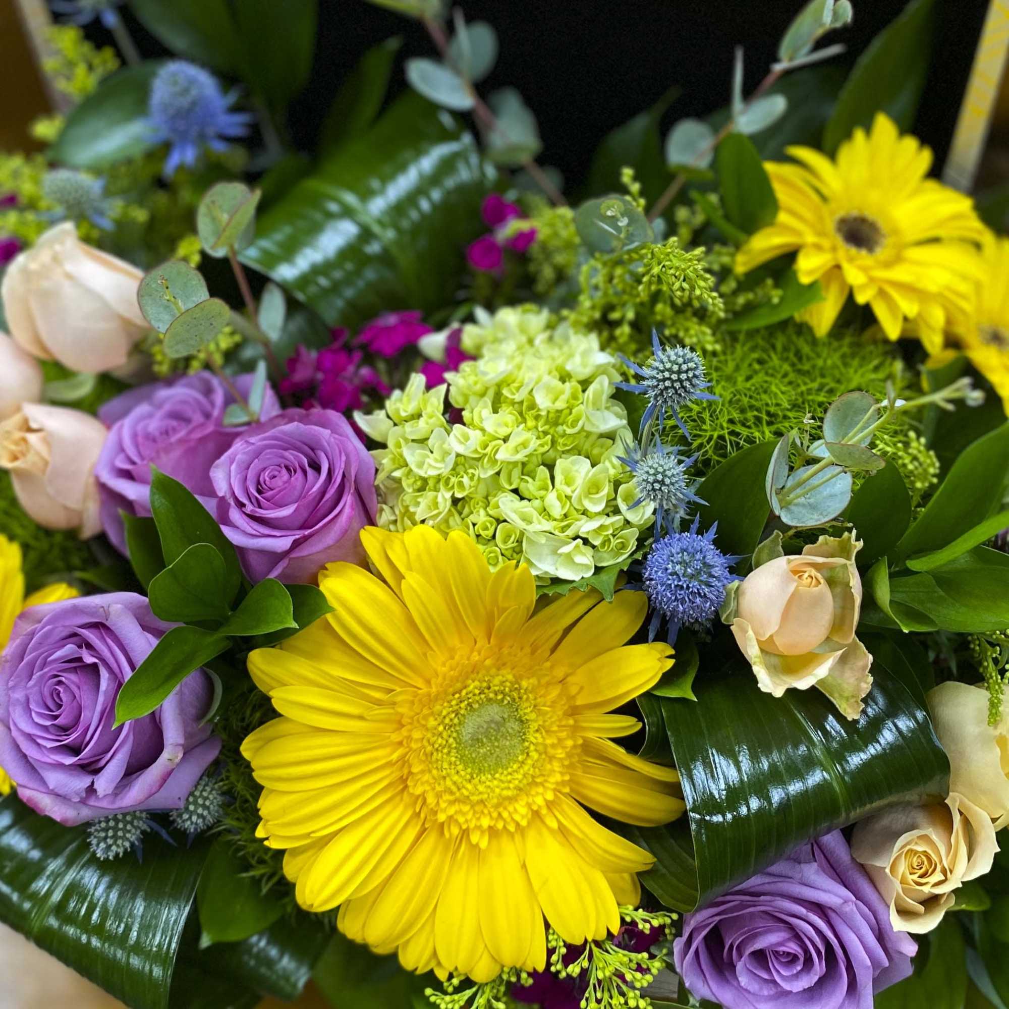 Bouquet of yellow gerbera daisies, purple roses, and pale hydrangea
