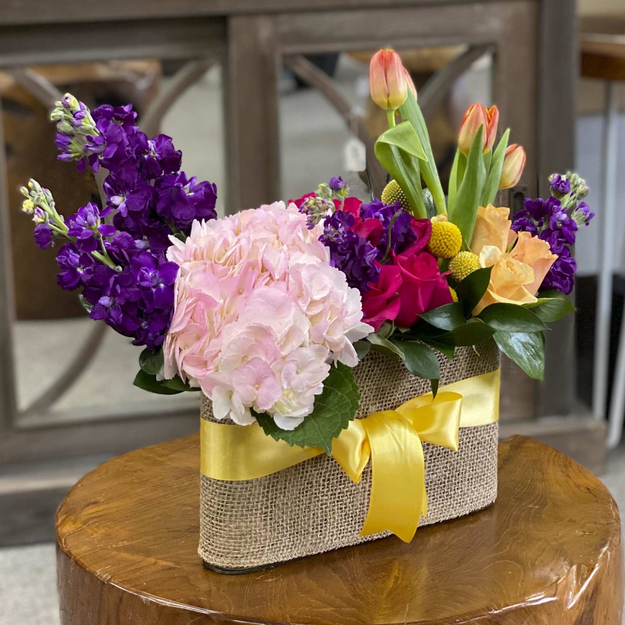 Mixed bouquet in a burlap-wrapped container with a yellow ribbon