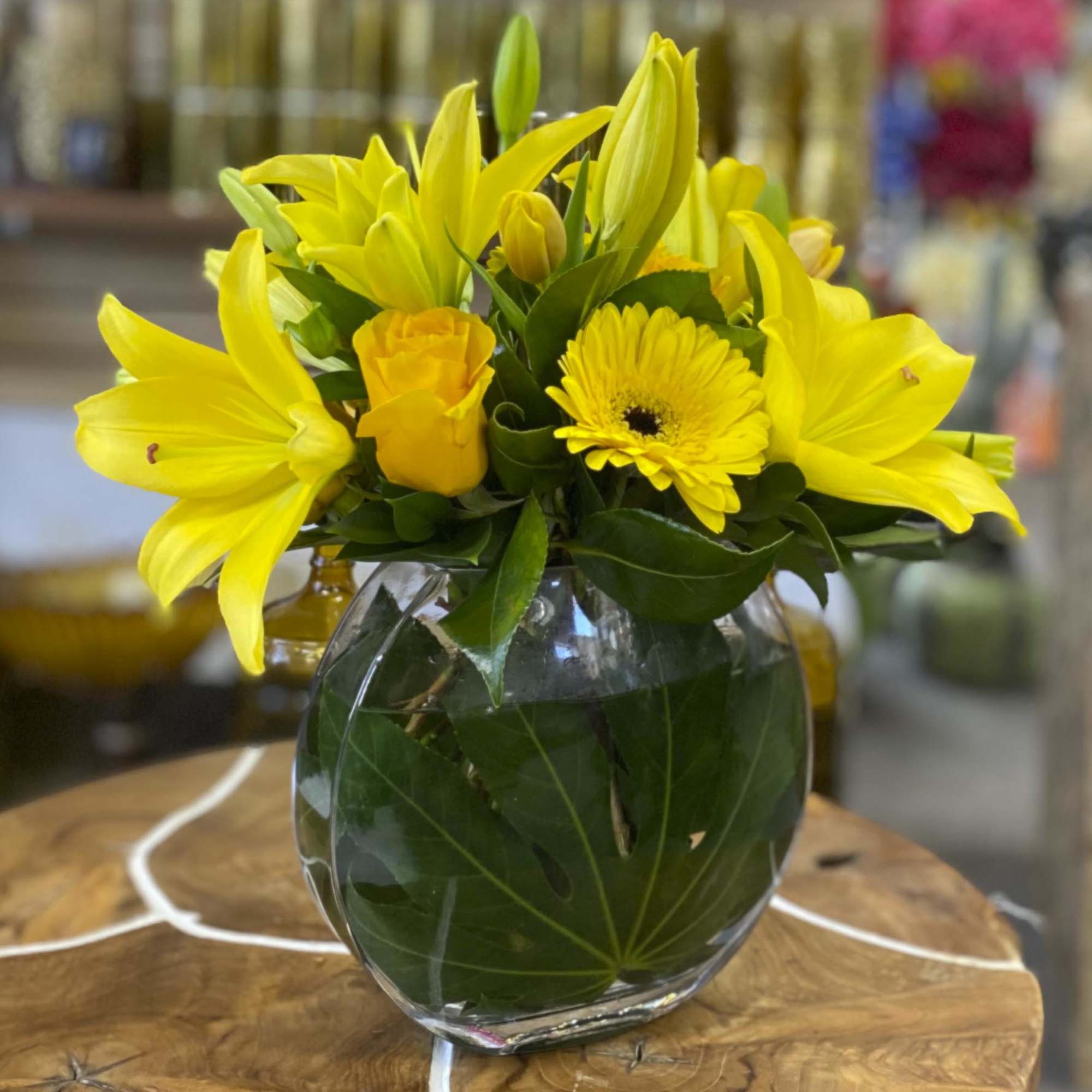 Yellow lilies and a gerbera daisy in a clear glass vase