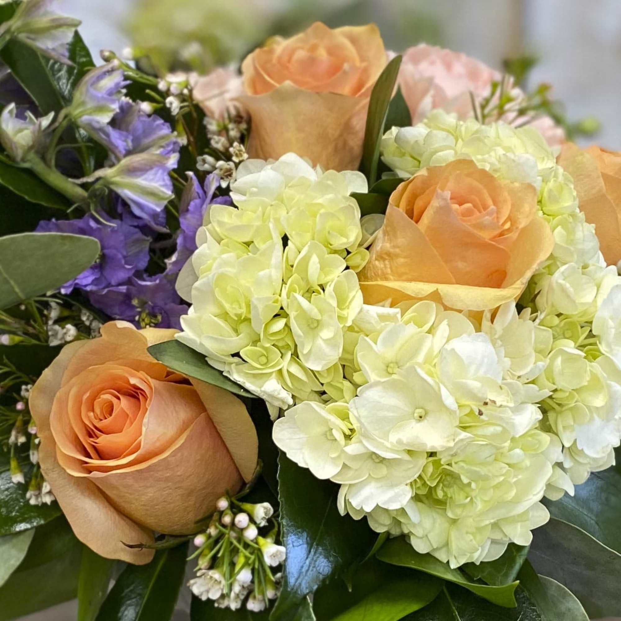 Bouquet of peach roses and pale hydrangeas with purple flowers