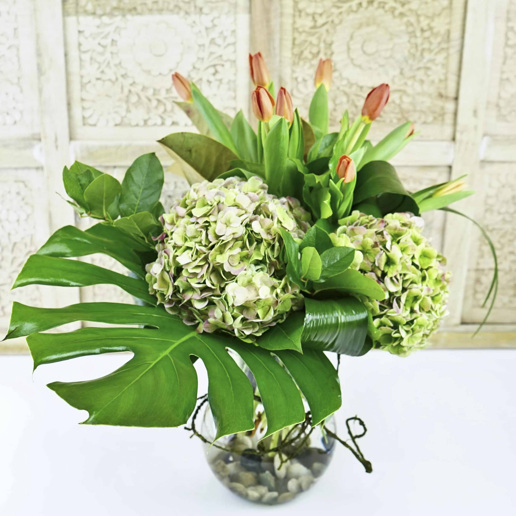 Bouquet of green hydrangeas and tulips in a glass vase
