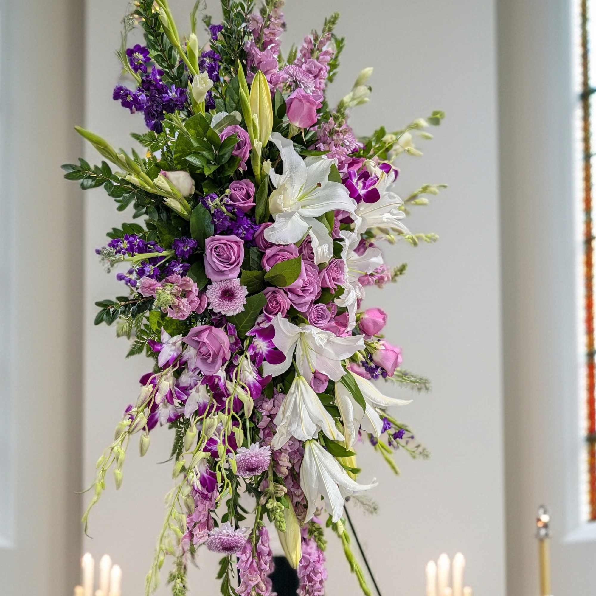 Tall purple and white floral spray on an easel in a church