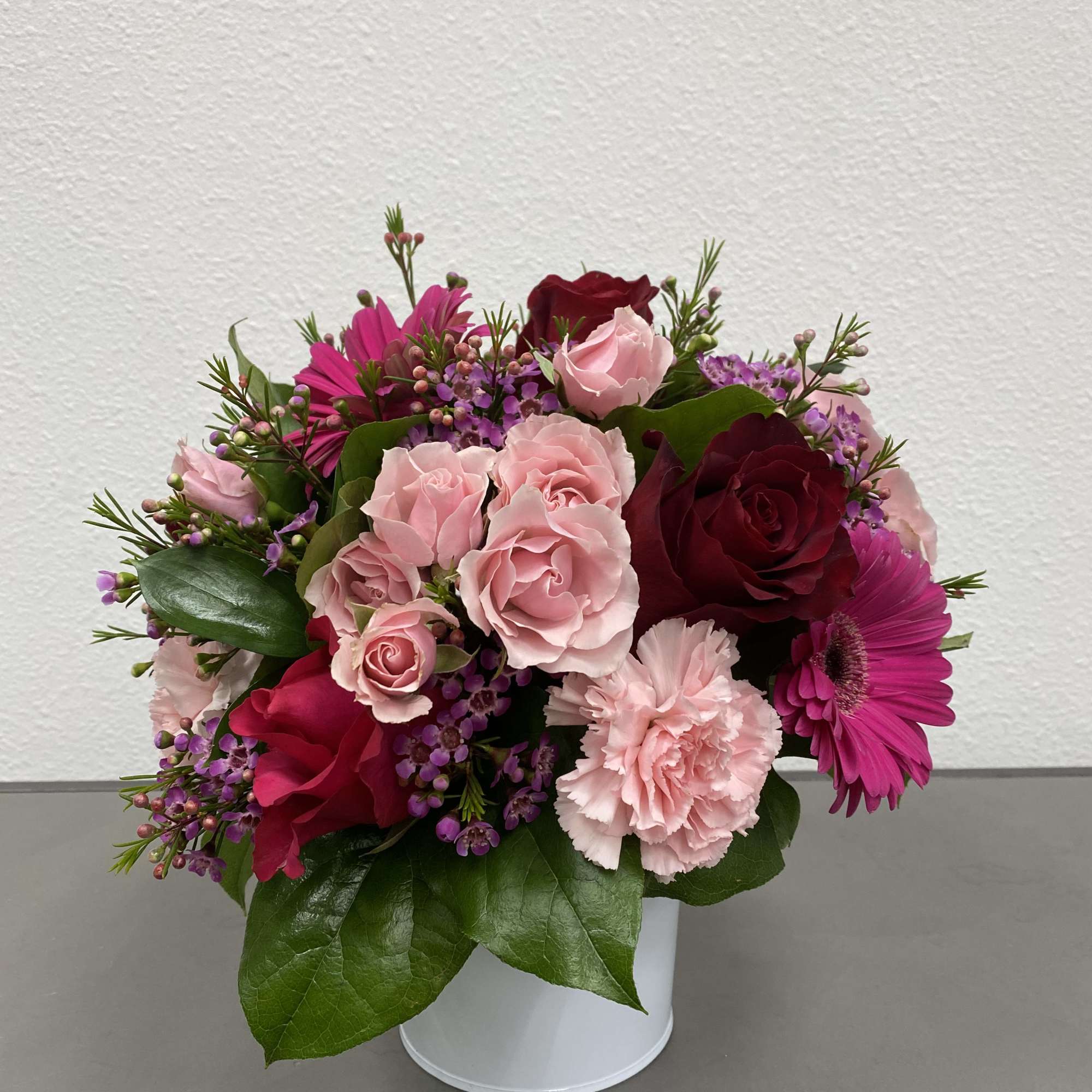 Pink and burgundy rose bouquet in a white container