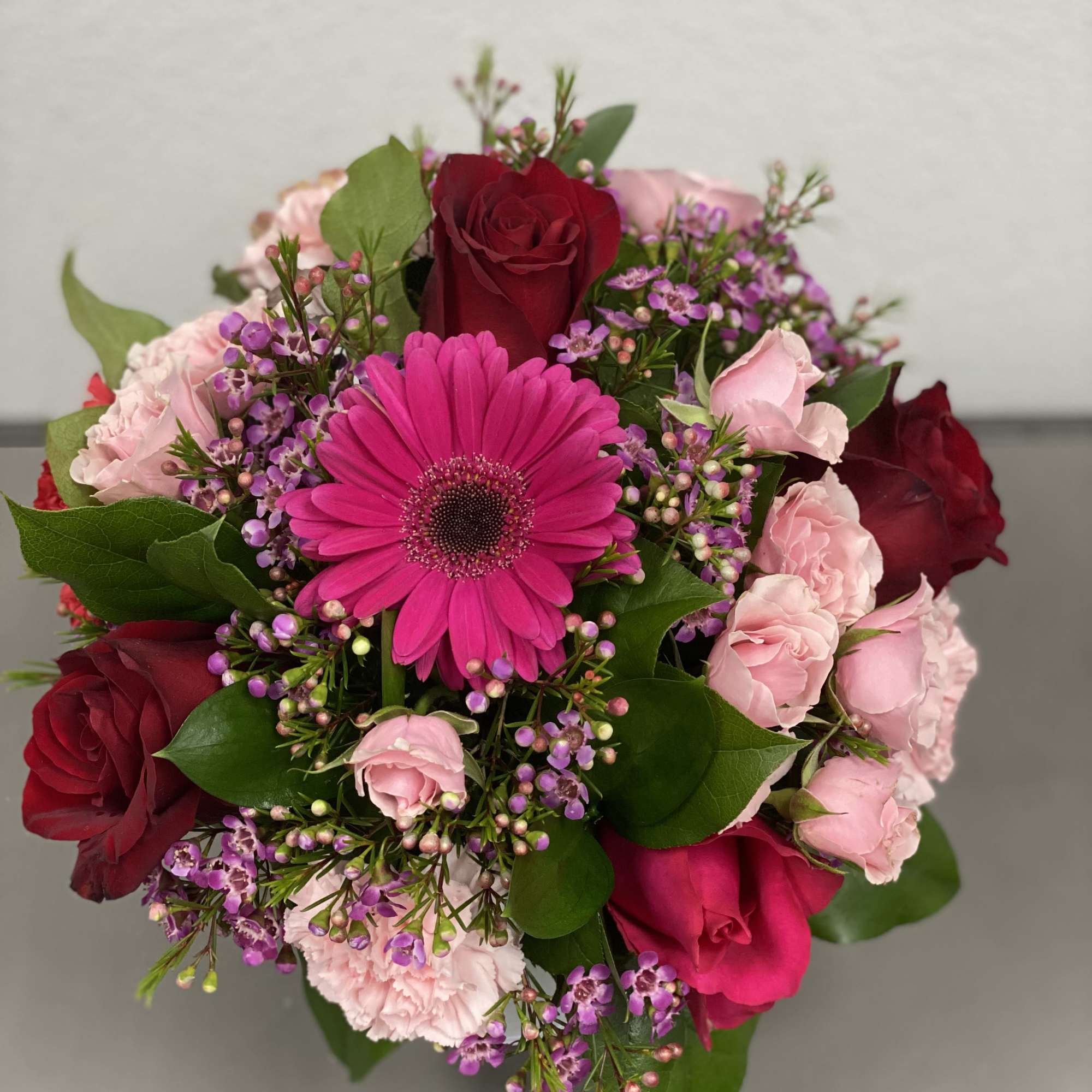 Bouquet of red and pink roses with a bright pink gerbera daisy