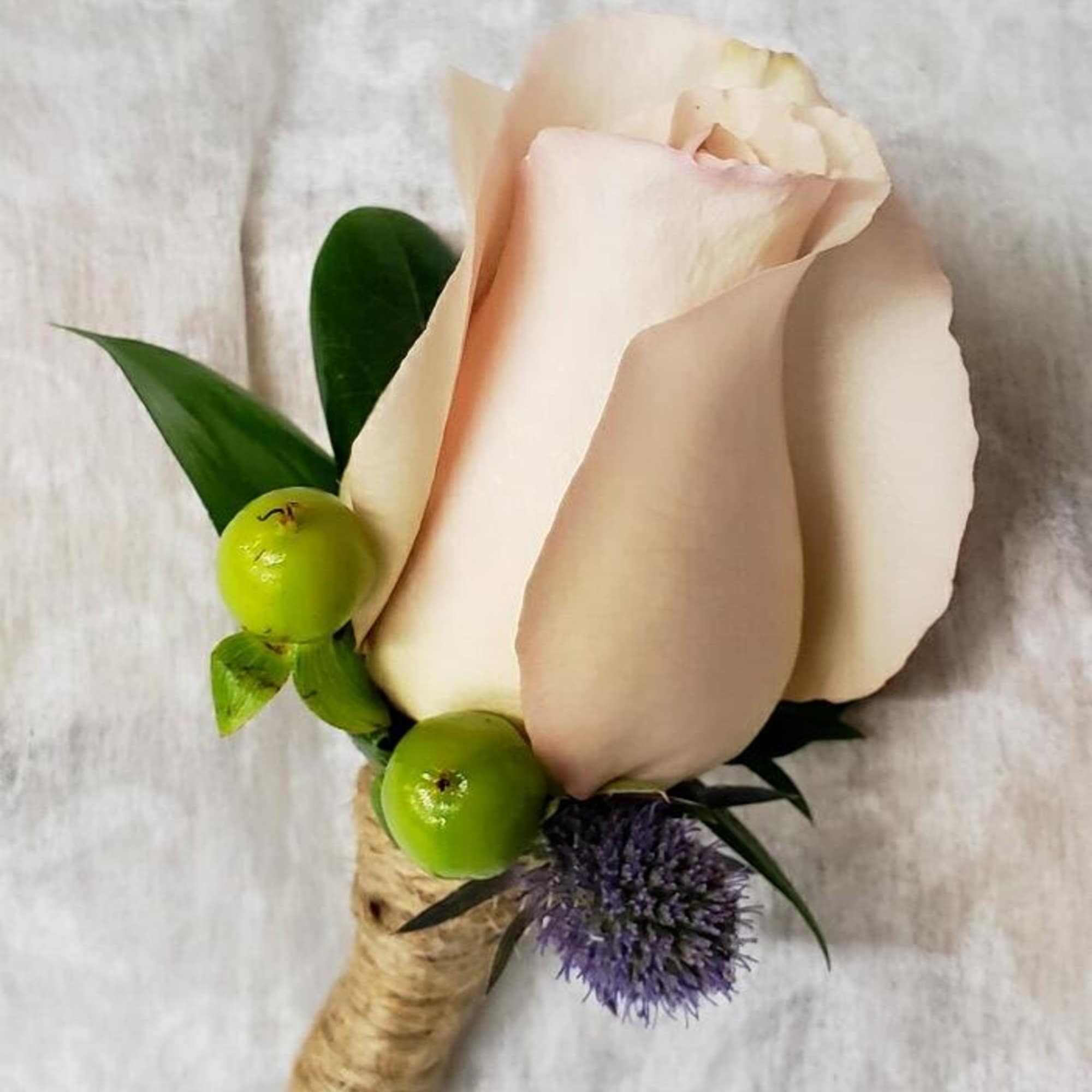 Single pale pink rose boutonniere with green berries and purple accent flower