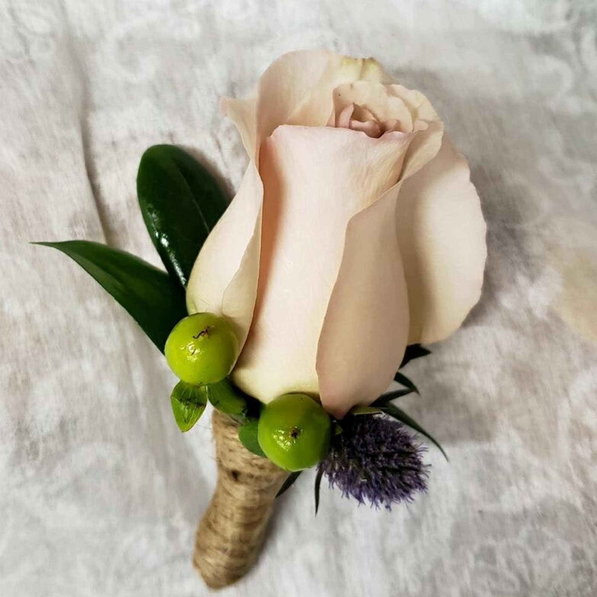Single pale rose boutonniere with green berries and a purple accent