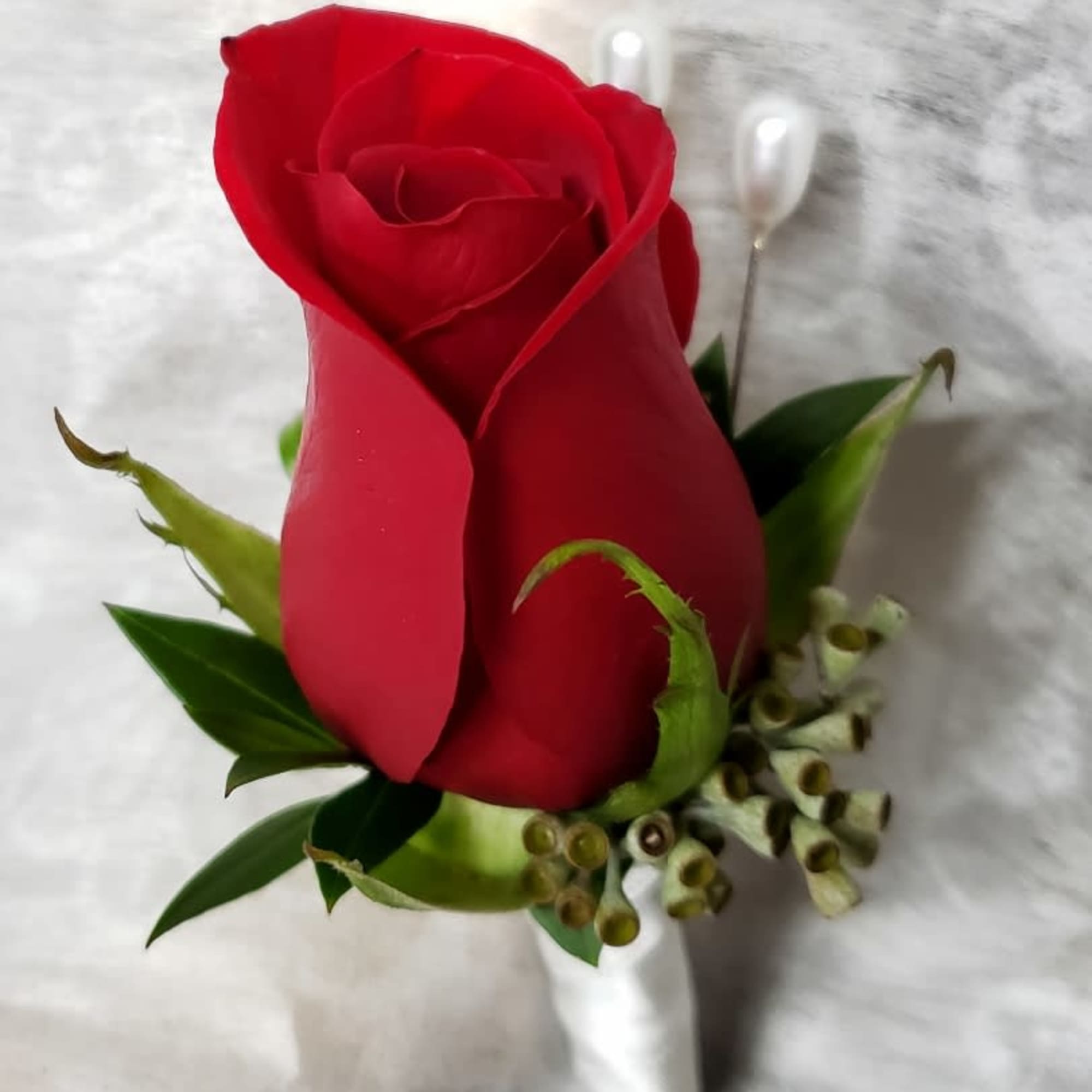 Single red rose boutonniere with green accents