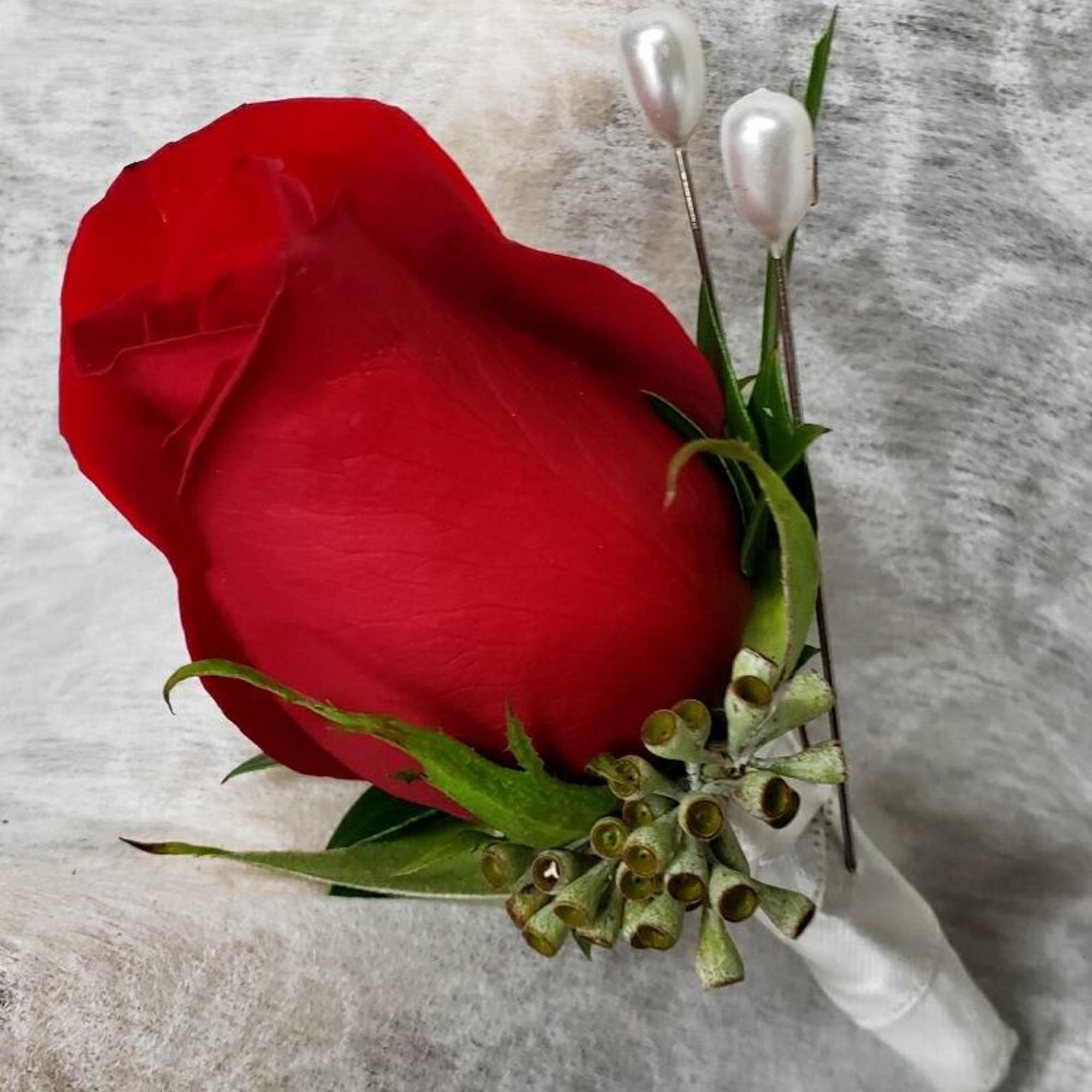 Red rose boutonniere with white pearl accents and green foliage
