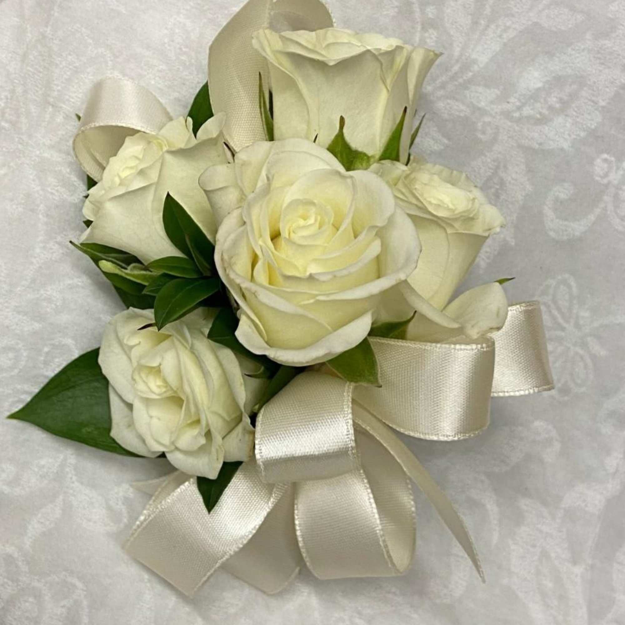 White rose bouquet with cream ribbon on white fabric