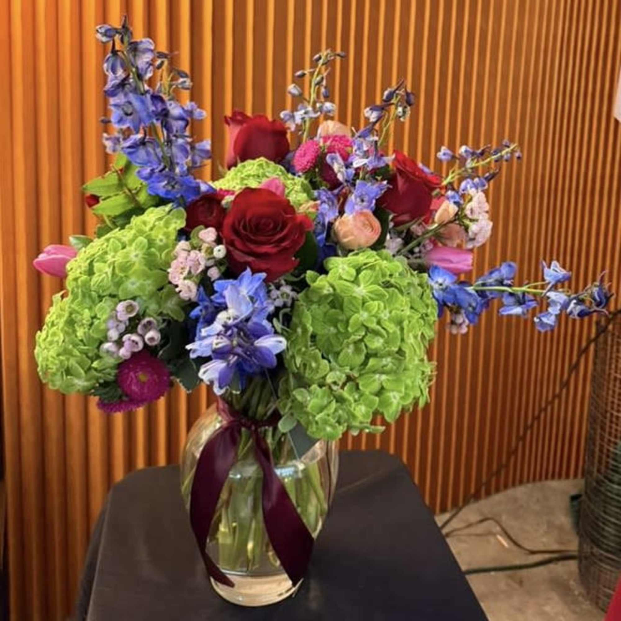 Bouquet of red roses, green hydrangeas, and blue flowers in a glass vase, photo 2 of 2
