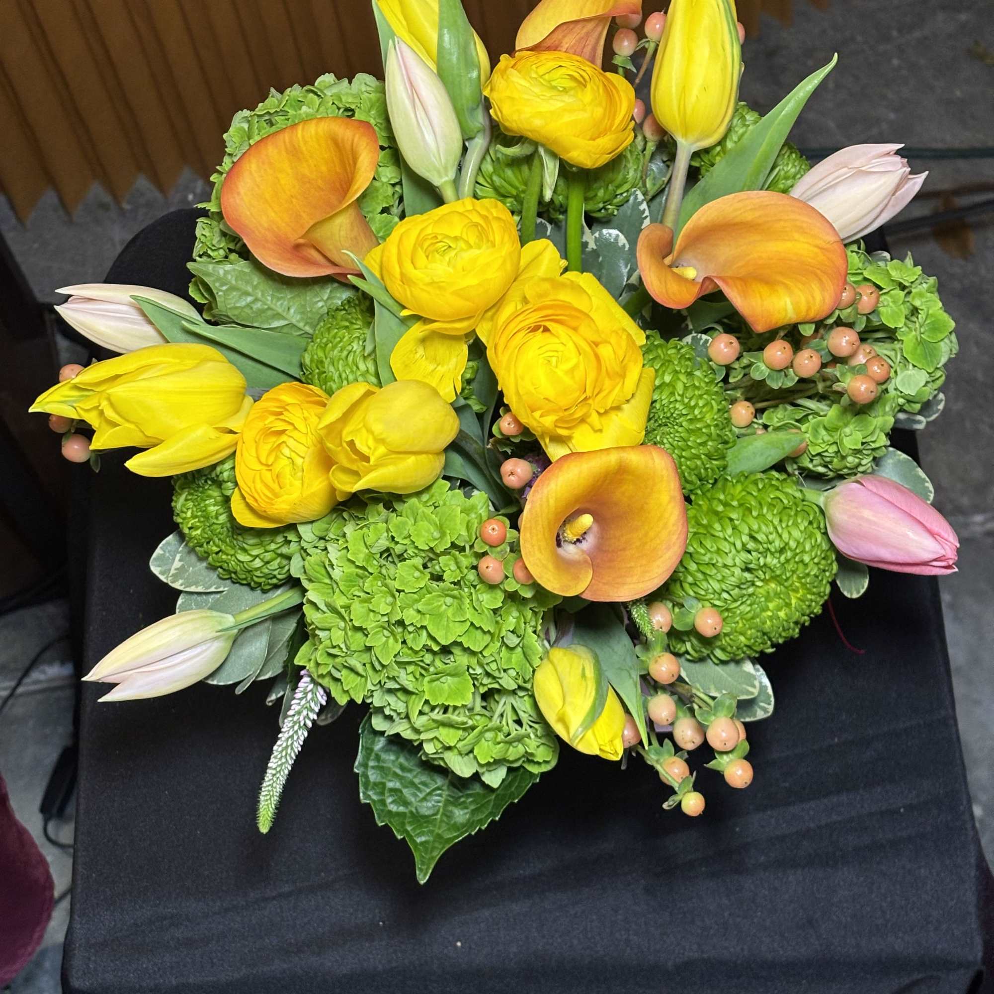 Bouquet of yellow and orange flowers with green blooms and pink tulips