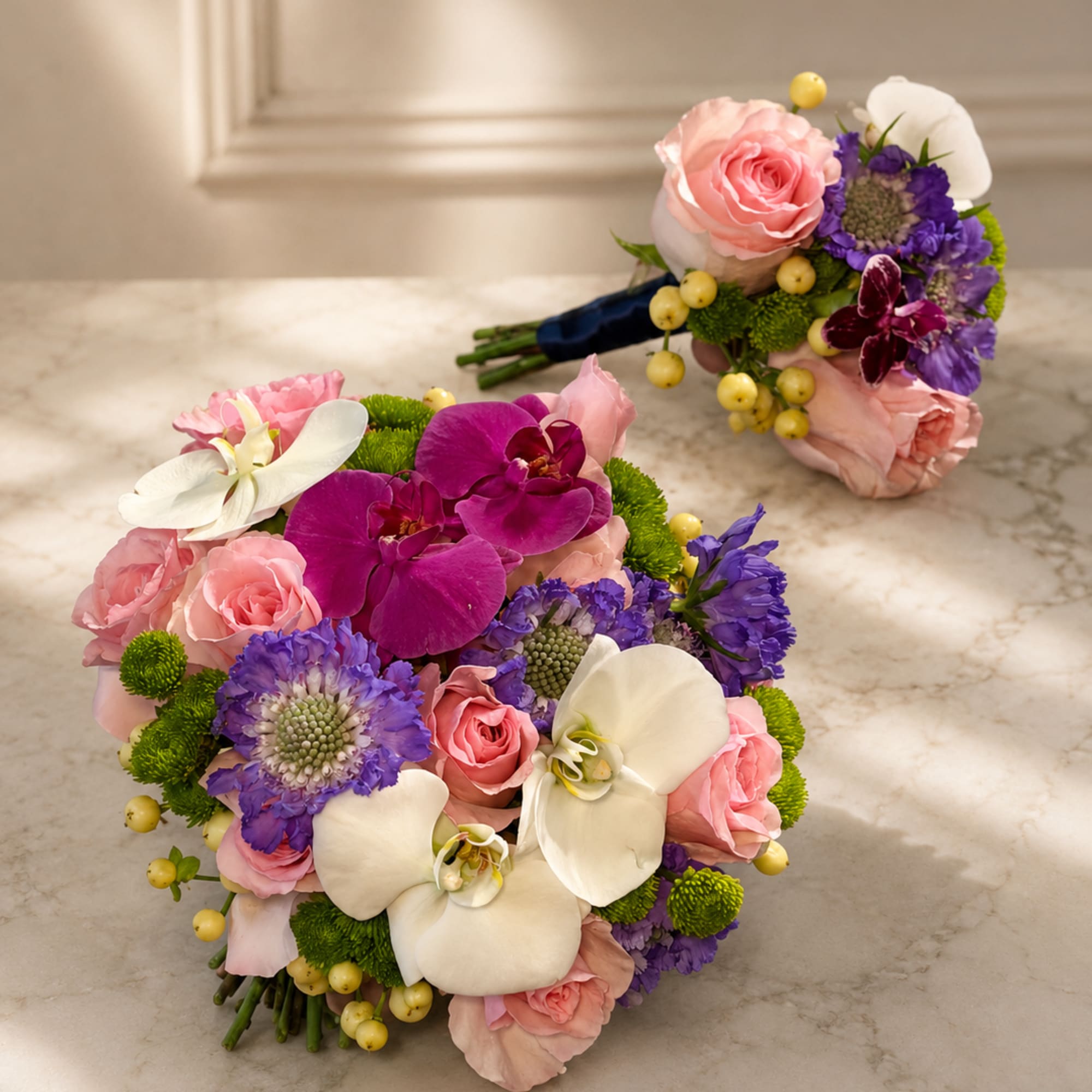 Two wedding bouquets with pink roses, white orchids, and purple flowers