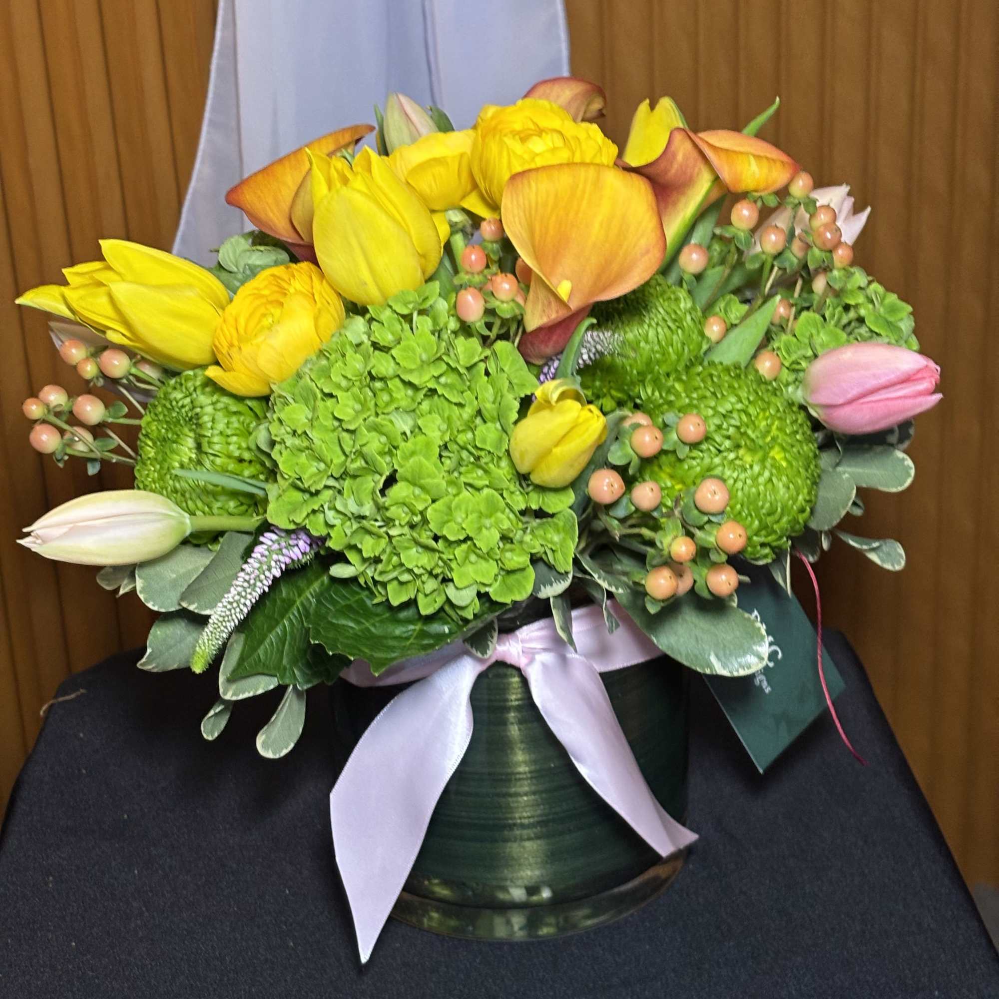 Bouquet of yellow tulips, green hydrangea, and orange calla lilies in a vase