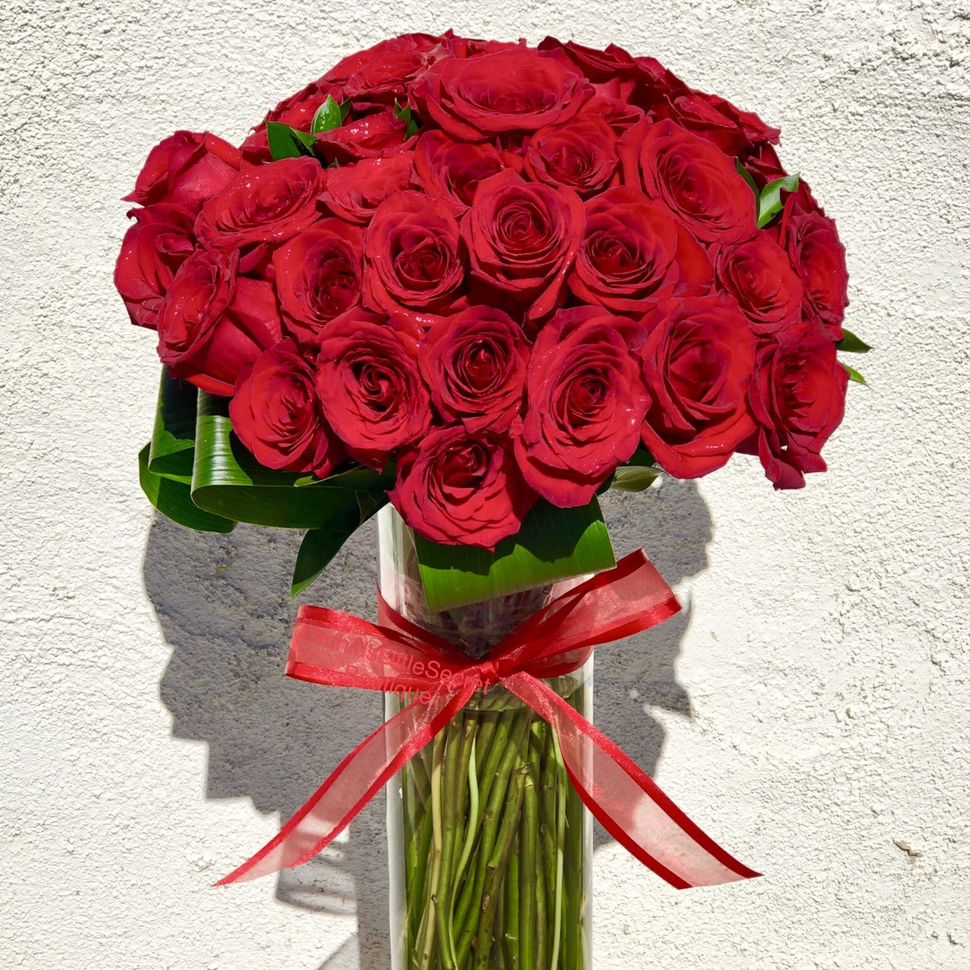 Bouquet of red roses in a clear glass vase with a red ribbon