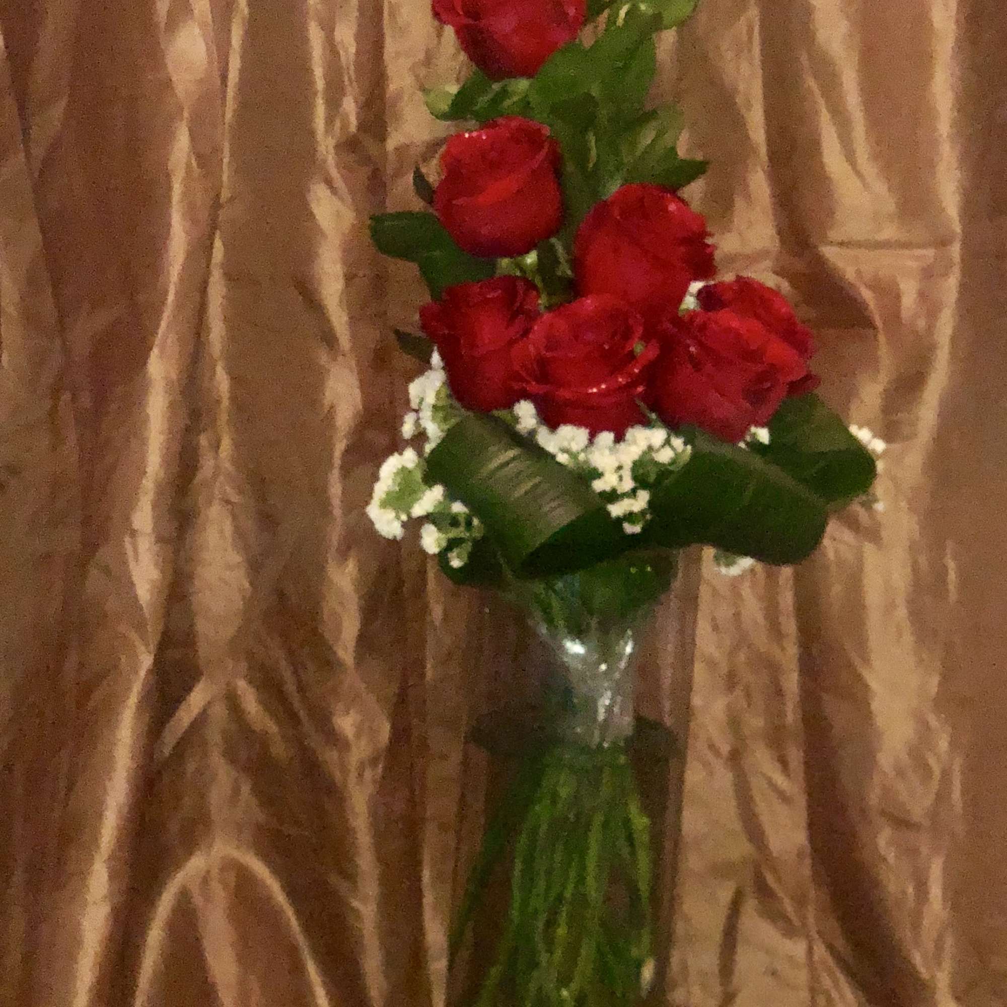 Tall bouquet of red roses in a glass vase with white filler flowers