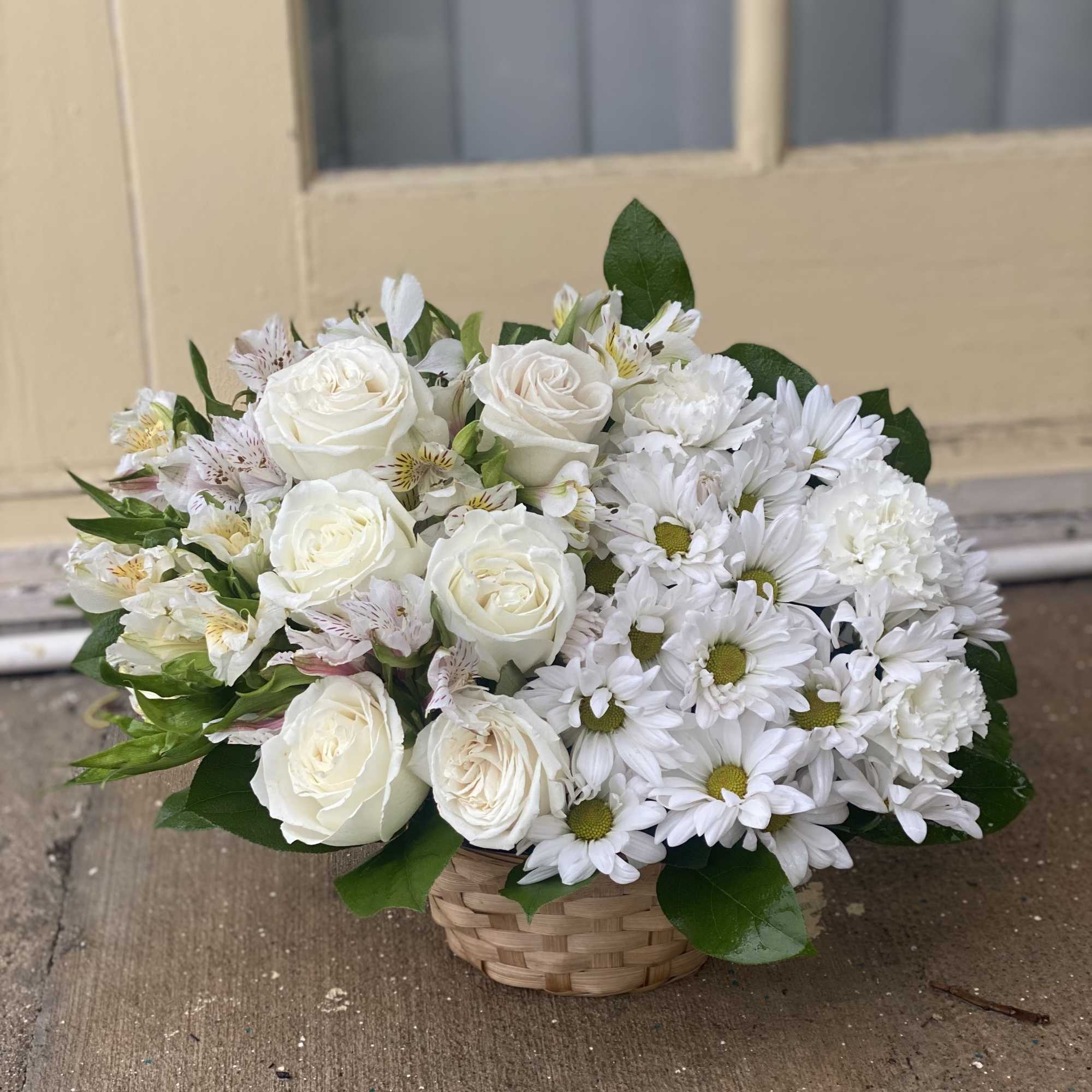 White roses and daisies arranged in a woven basket