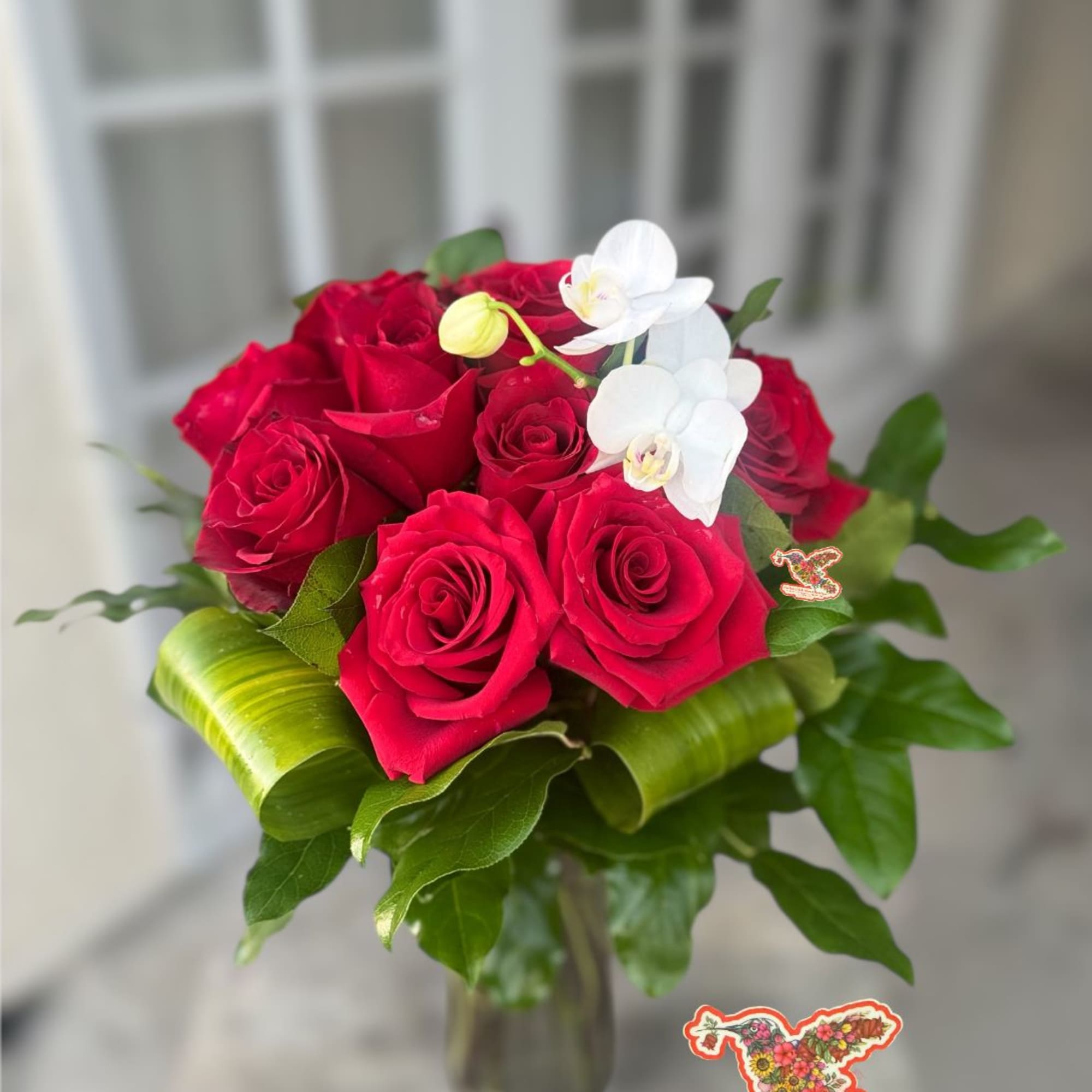 Red roses and white orchids arranged in a glass vase