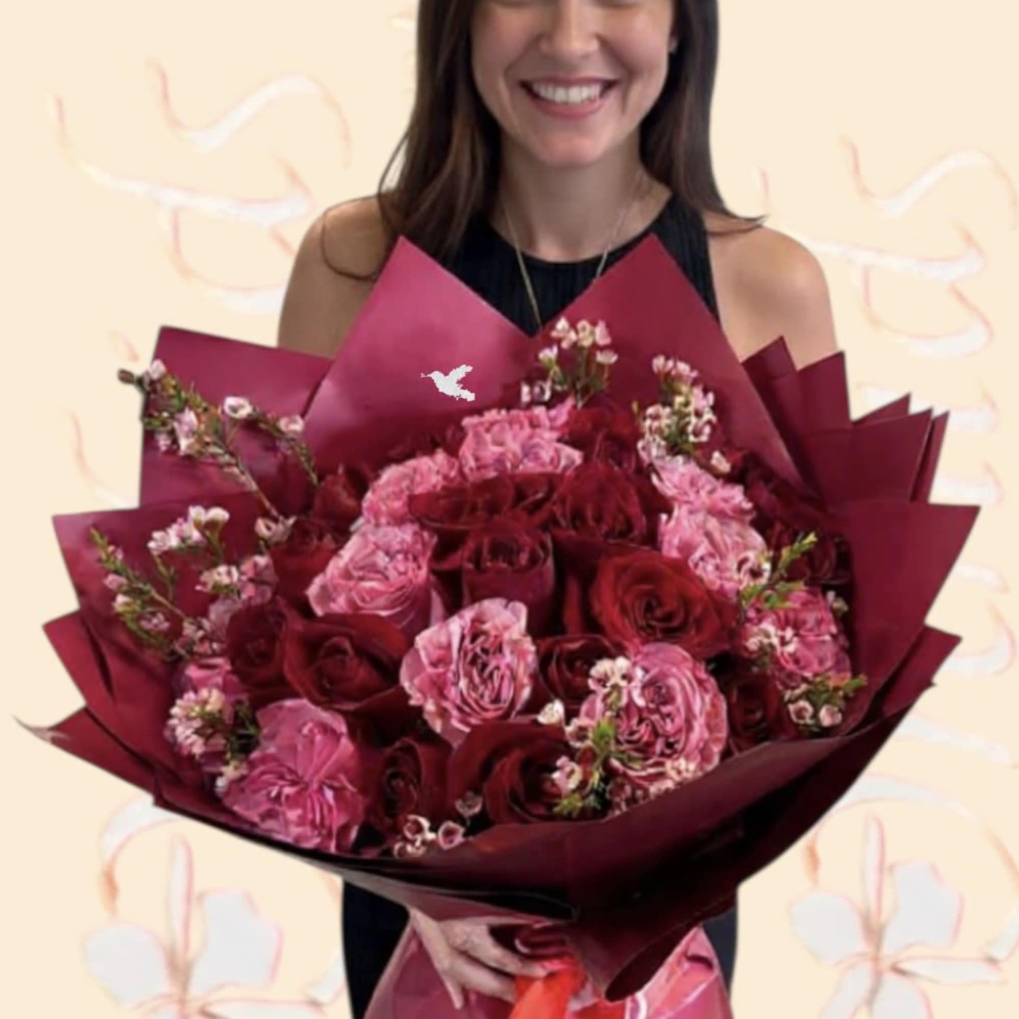 Woman holding a large bouquet of pink and red roses wrapped in burgundy paper