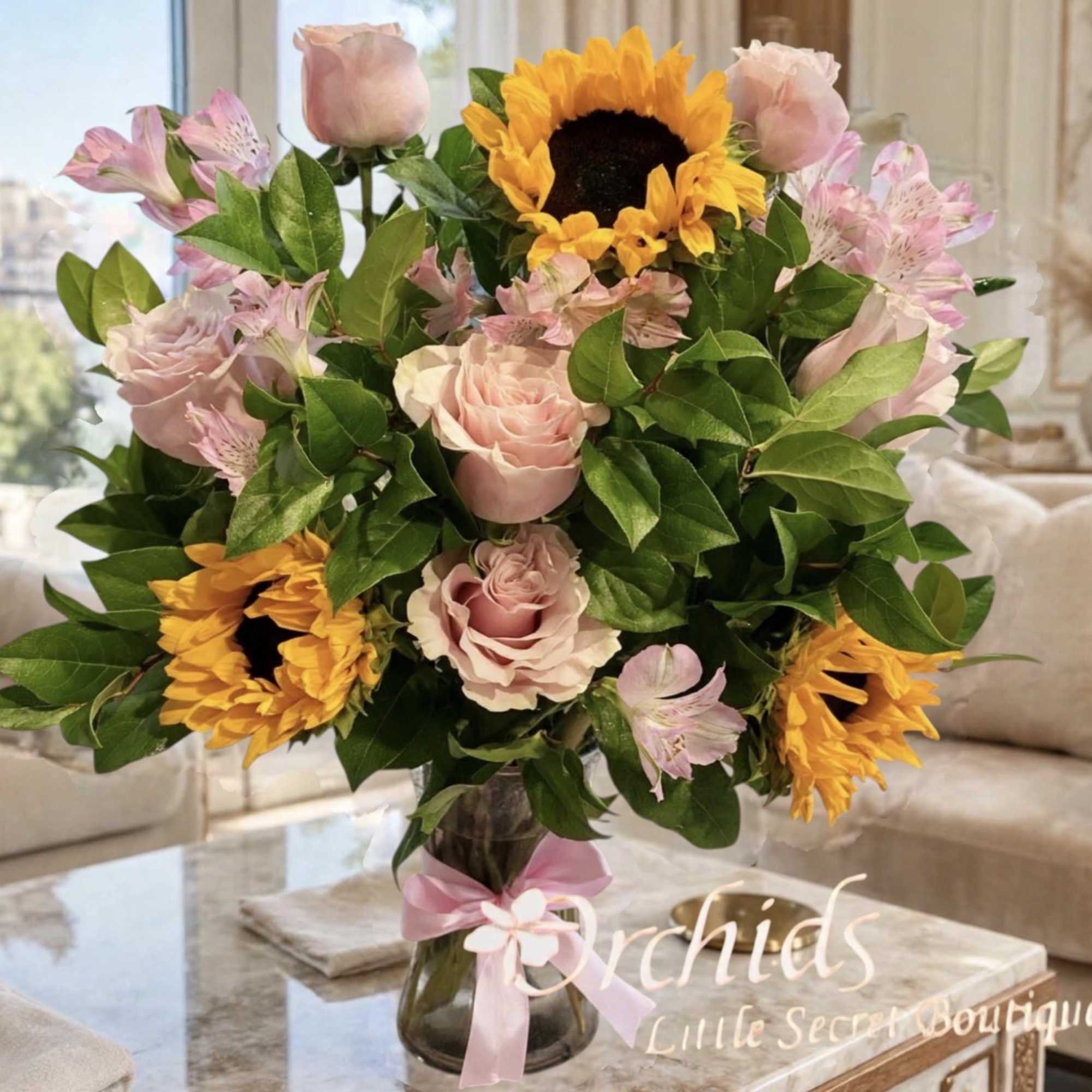 Bouquet of pink roses, sunflowers, and alstroemeria in a glass vase